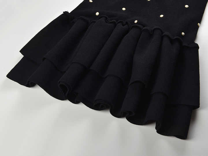 Sleeveless black mini dress featuring delicate pearl embellishments and a playful tiered ruffle skirt