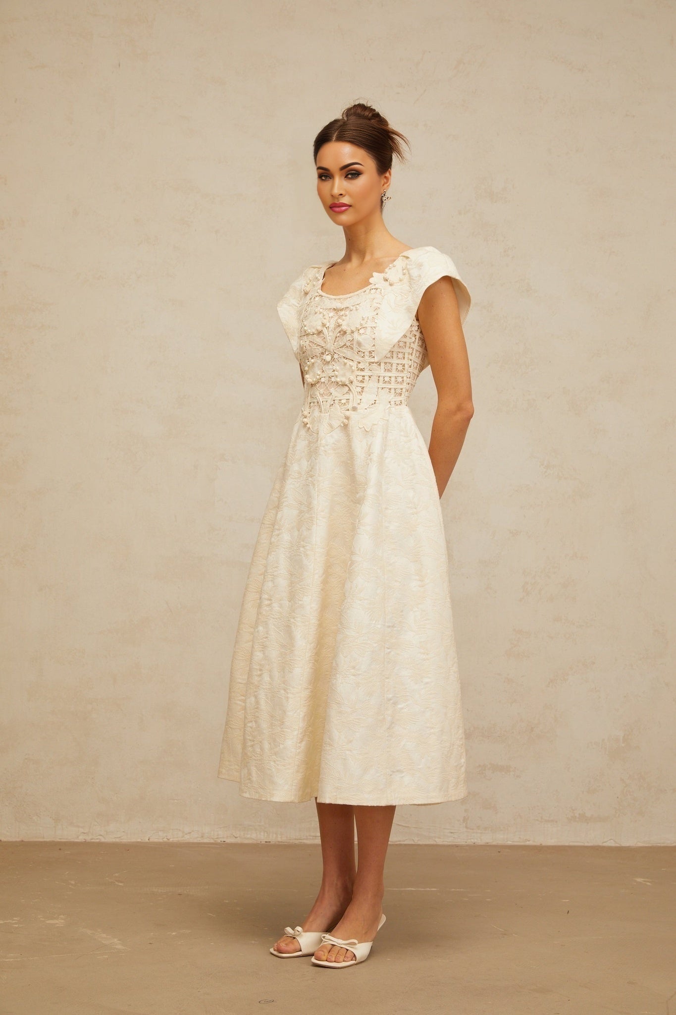 A beige midi dress with delicate floral embroidery and subtle embellishments featuring a feminine silhouette and neutral tones