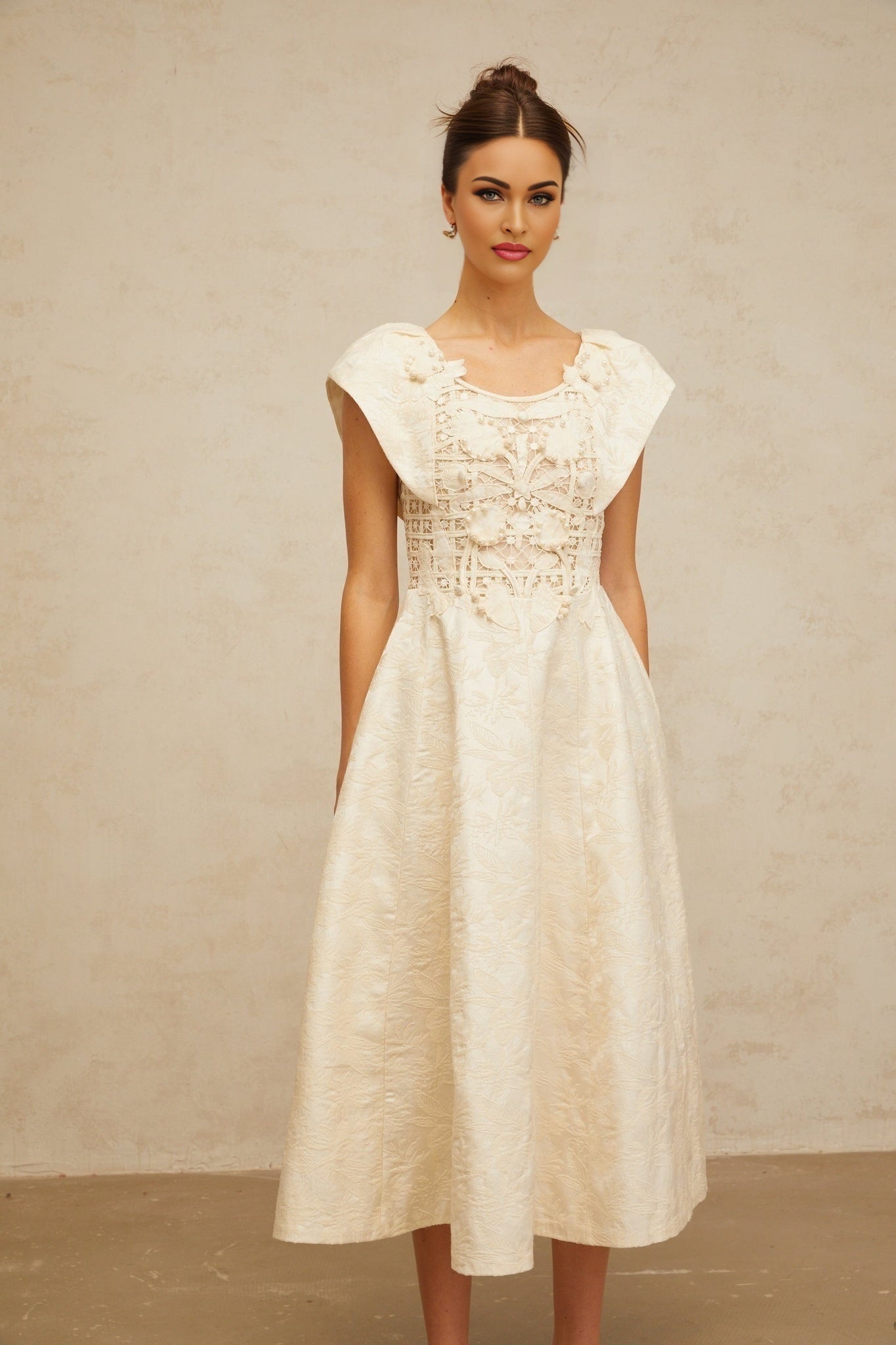 A beige midi dress with delicate floral embroidery and subtle embellishments featuring a fitted bodice and flowing skirt