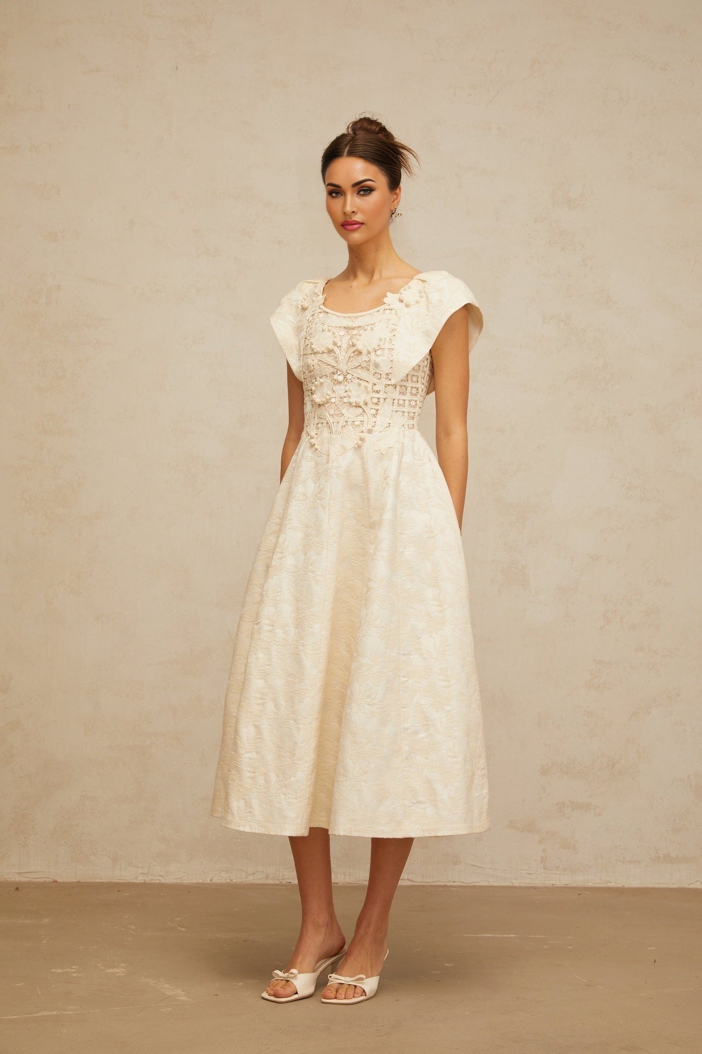 A beige midi dress with delicate floral embroidery and subtle embellishments featuring a fitted bodice and flowy skirt