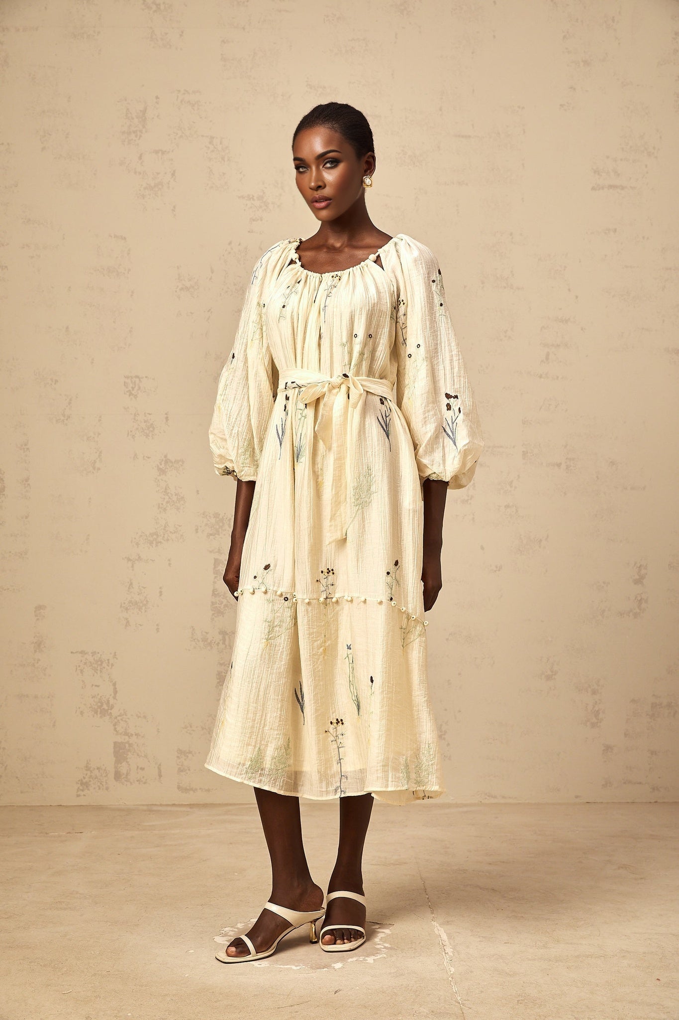 A beige midi dress with flower embroidery and beaded details featuring the Uranie design