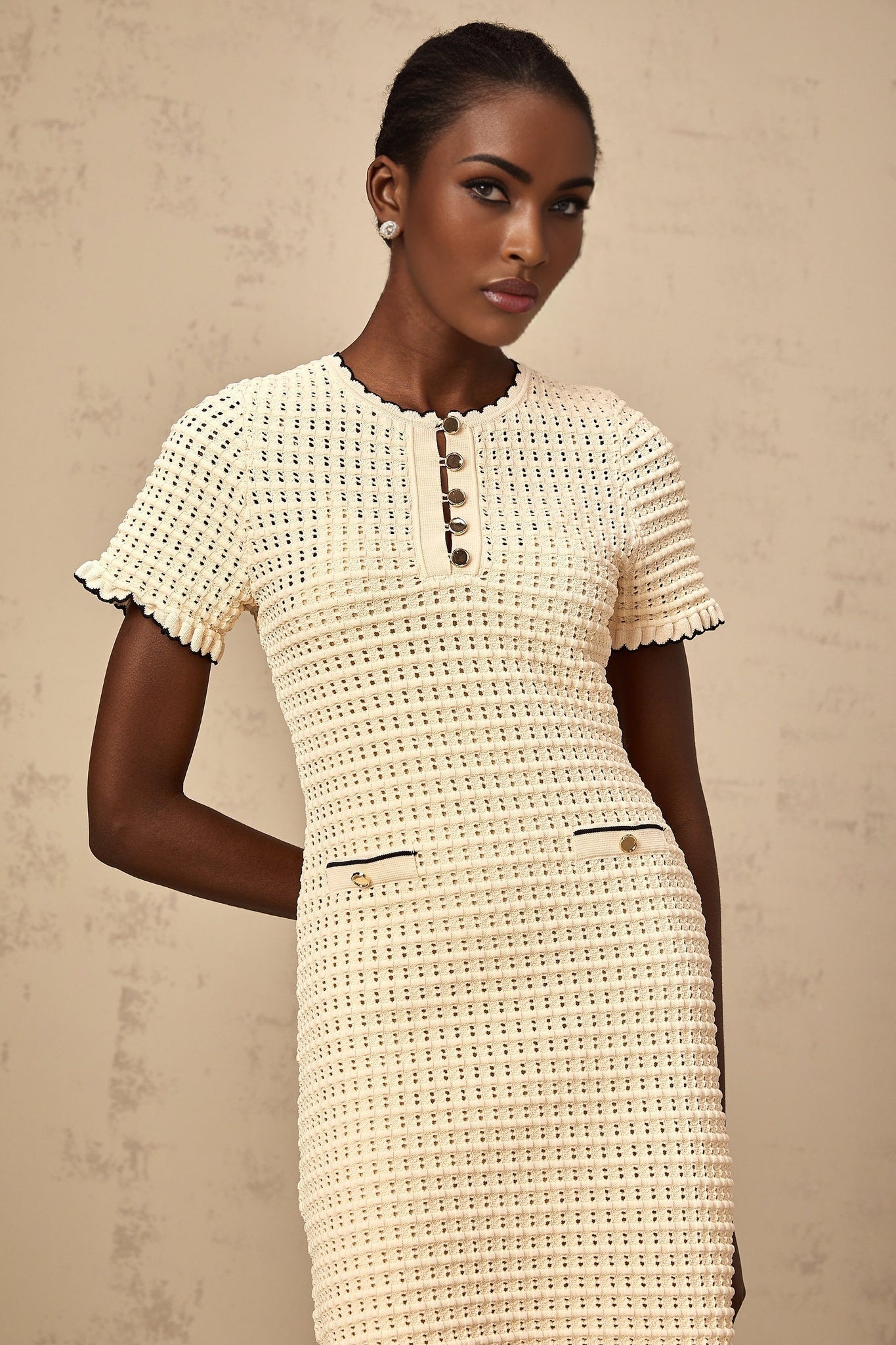 A beige mini dress with ruffled details and a delicate pointelle knit pattern featuring short sleeves and a fitted silhouette