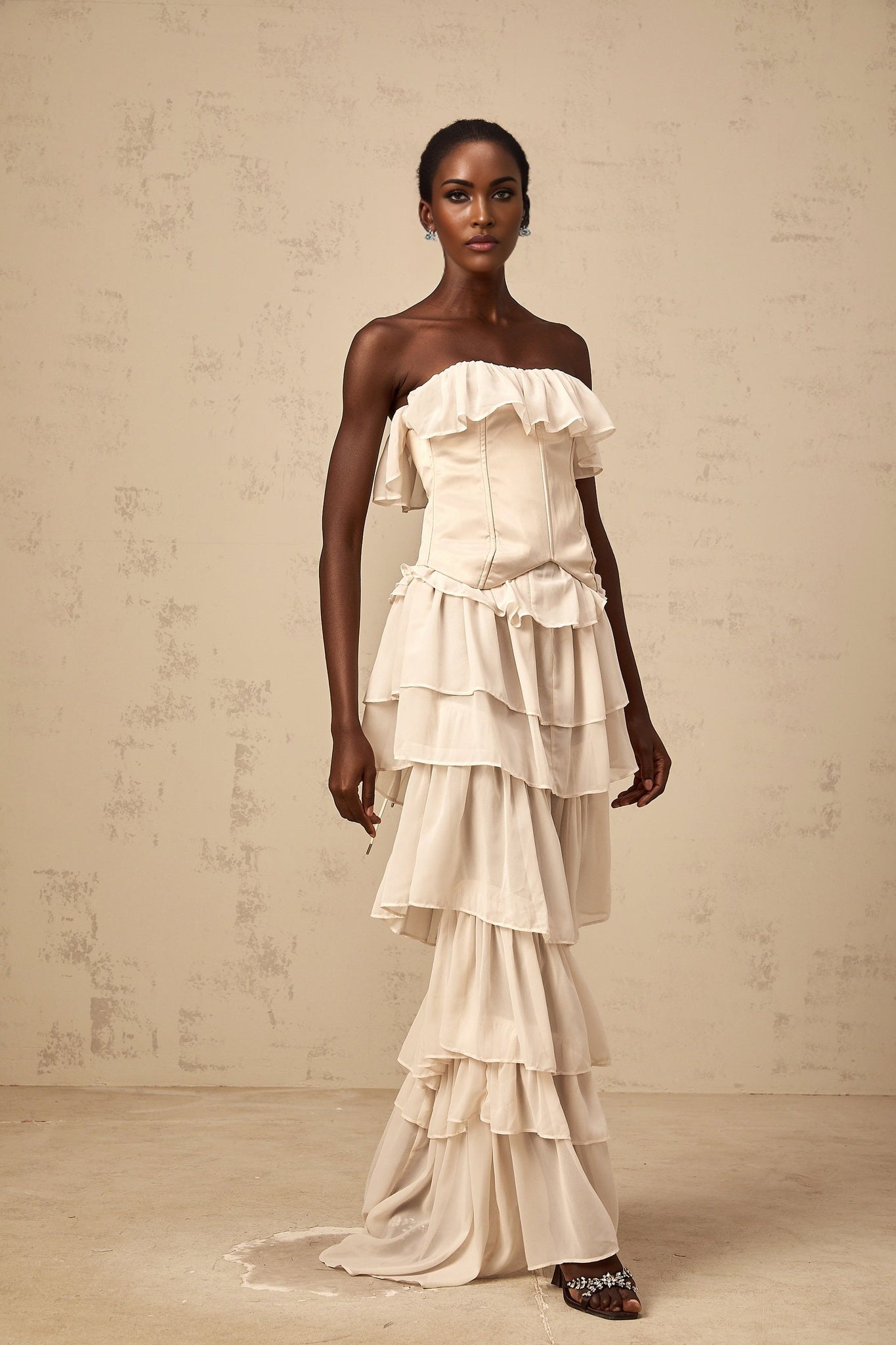 A beige offshoulder dress and corset set with tiered design featuring a matching top and bottom in a light cream color