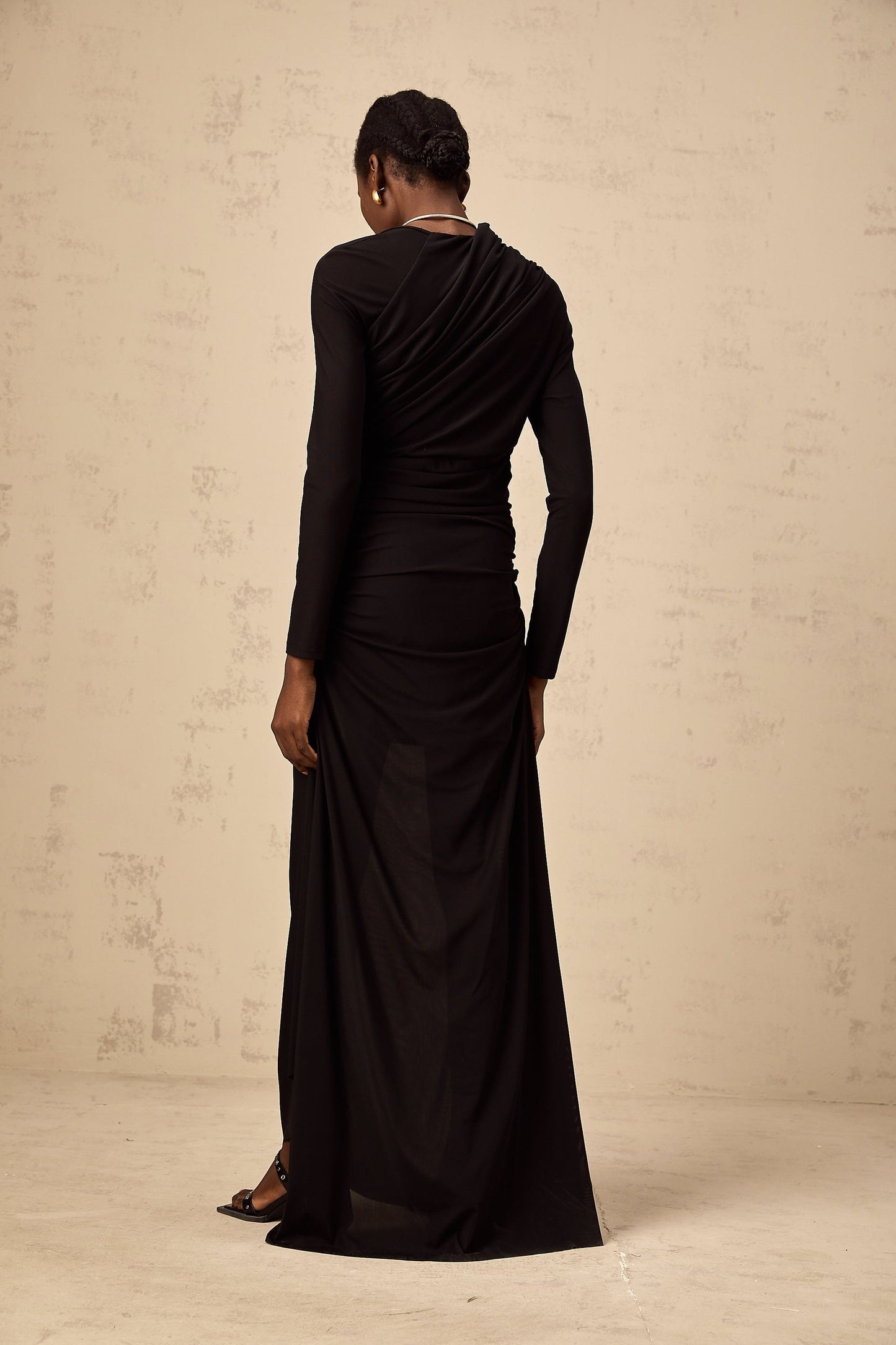 A black asymmetric maxi dress with tulle fabric and cut out details featuring a fitted bodice and flowing long skirt