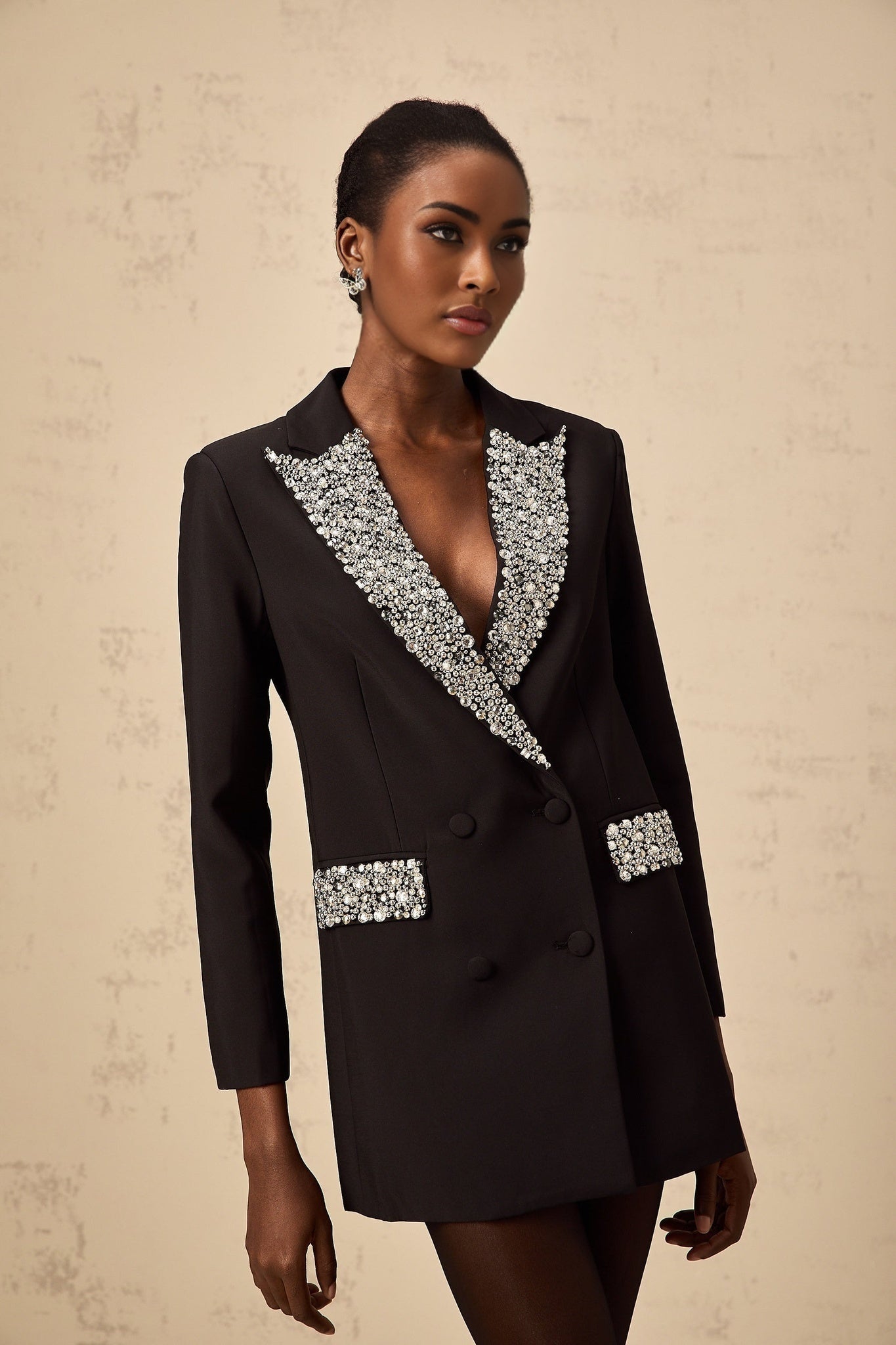 A black blazer adorned with crystal embellishments featuring a tailored fit and shimmering accents throughout the garment
