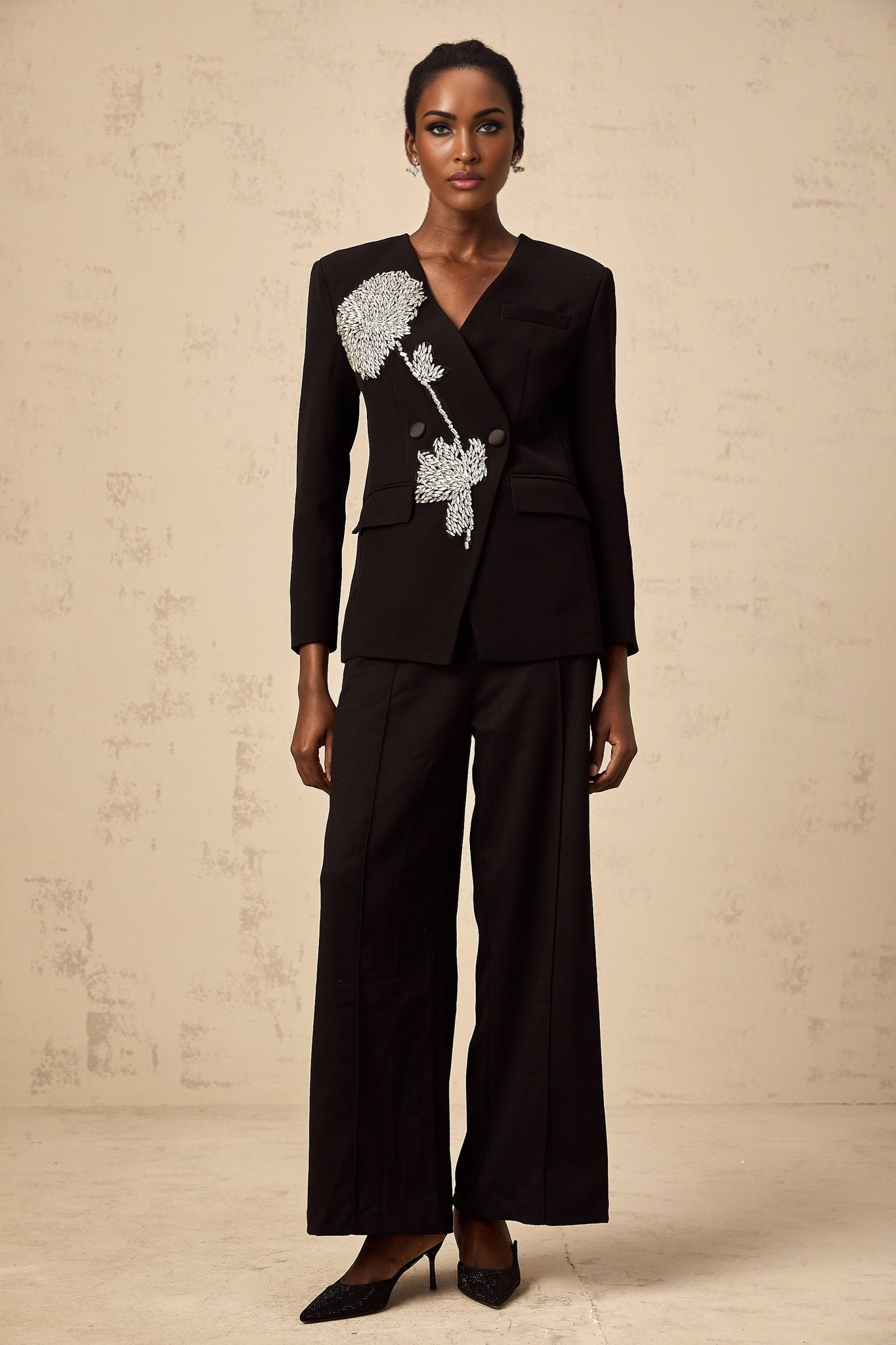 A black blazer adorned with floral embellishments featuring a flower motif design named Therese