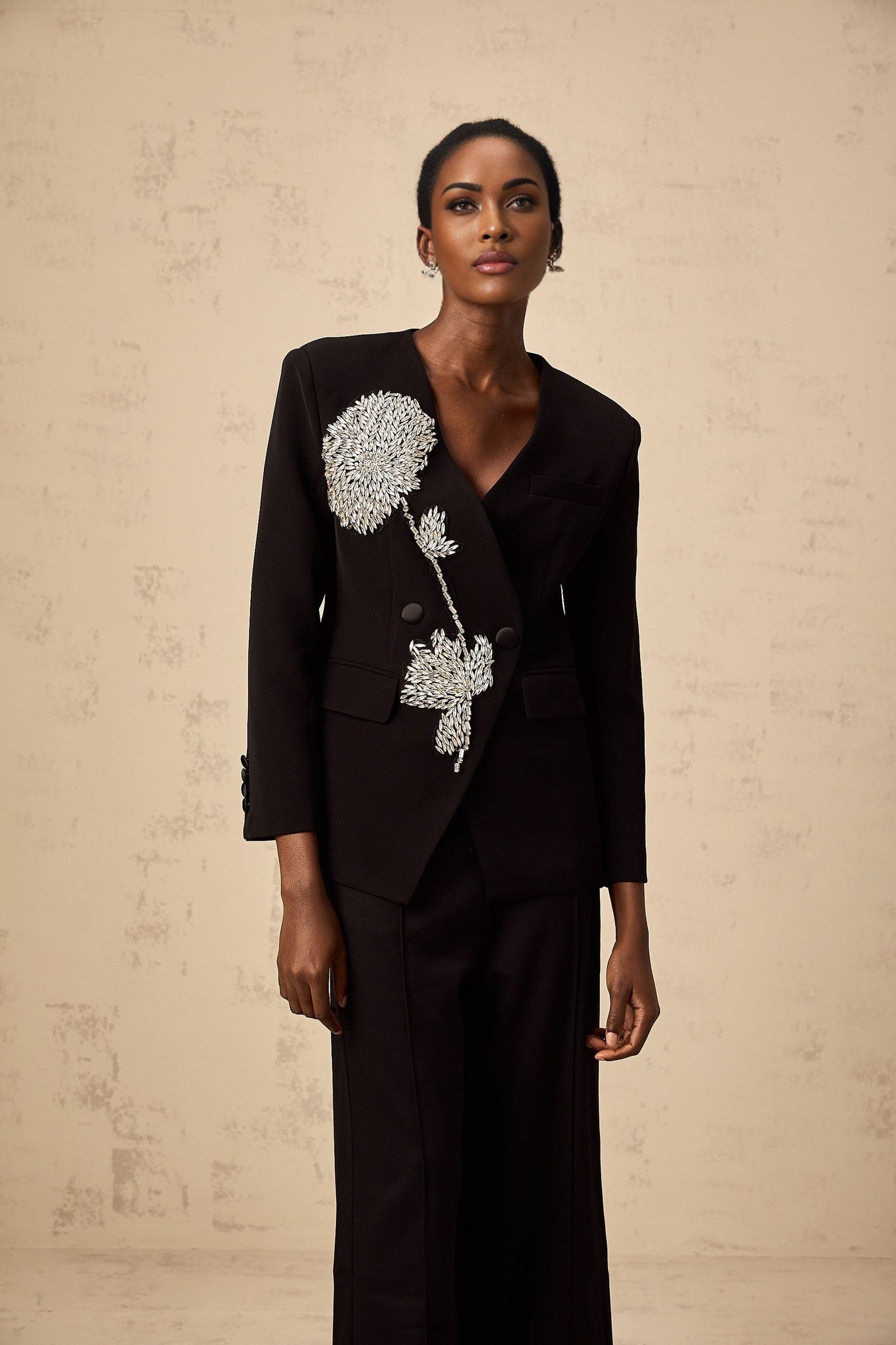 A black blazer adorned with floral embellishments featuring a flower motif design