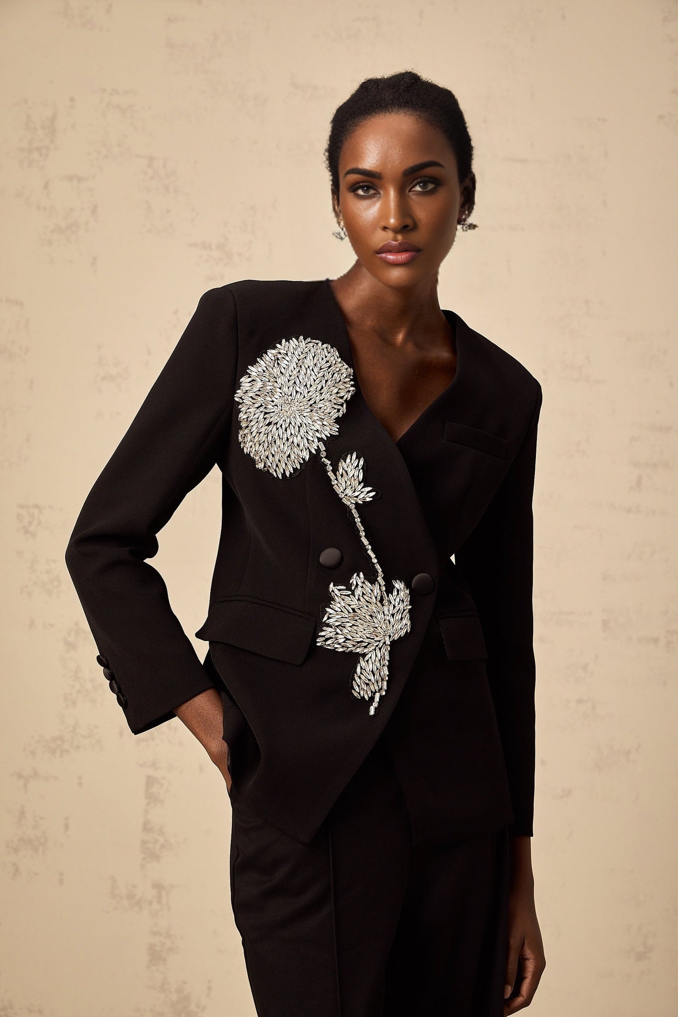 A black blazer adorned with floral motifs featuring embellished flower patterns throughout the garment