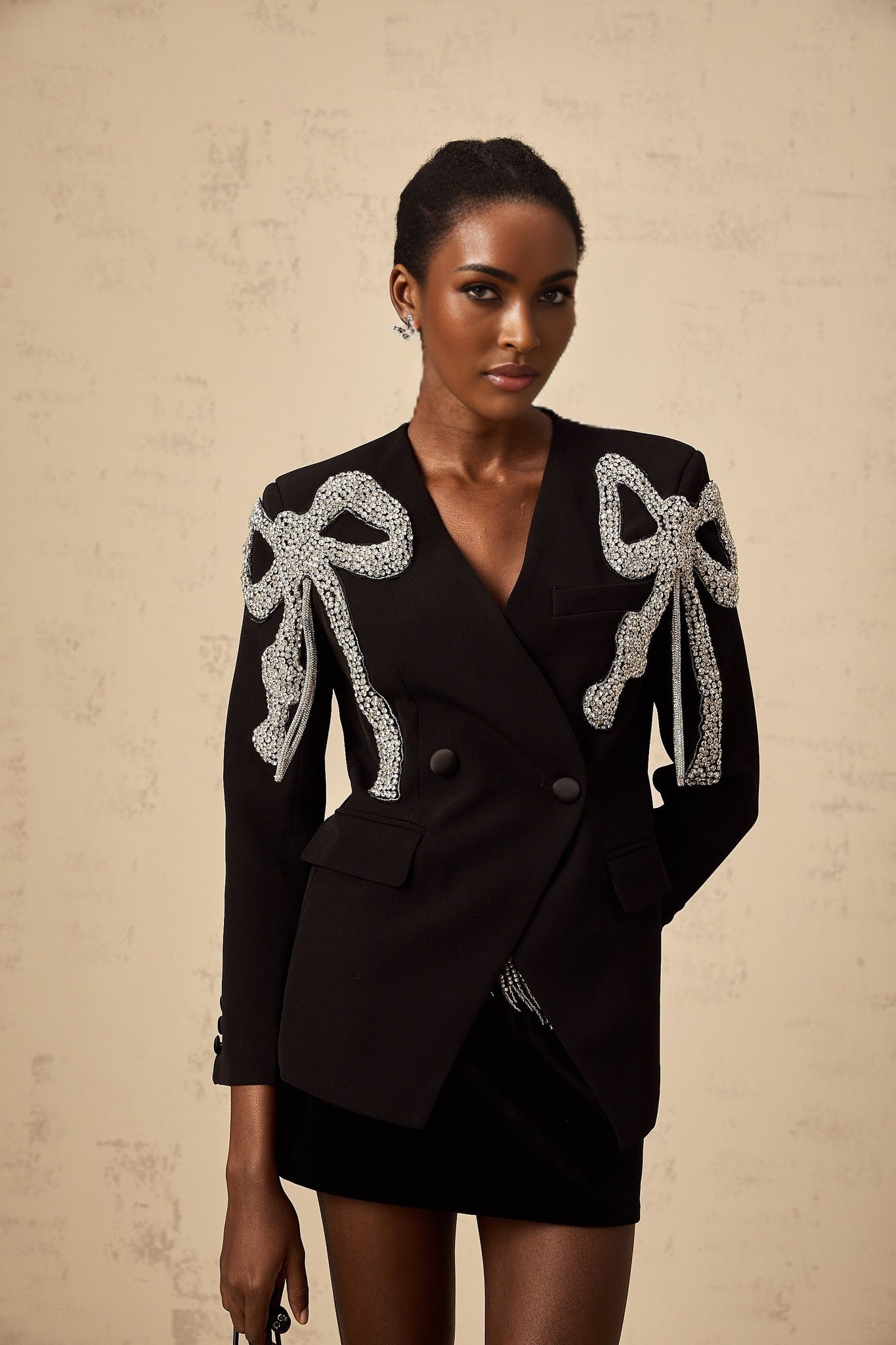 A black blazer featuring bowmotif embellishments and a tailored silhouette