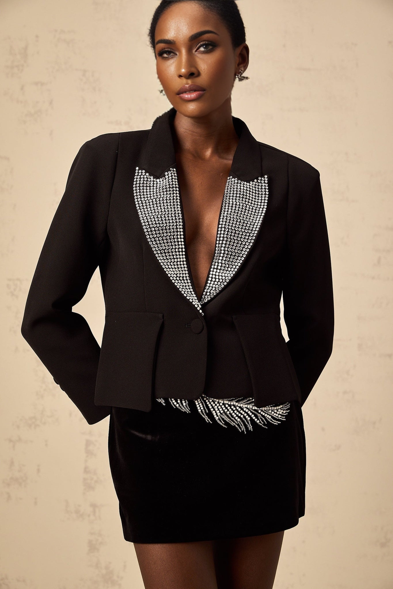A black blazer with a Vneck collar adorned with crystal embellishments featuring a sleek silhouette and sparkling accents