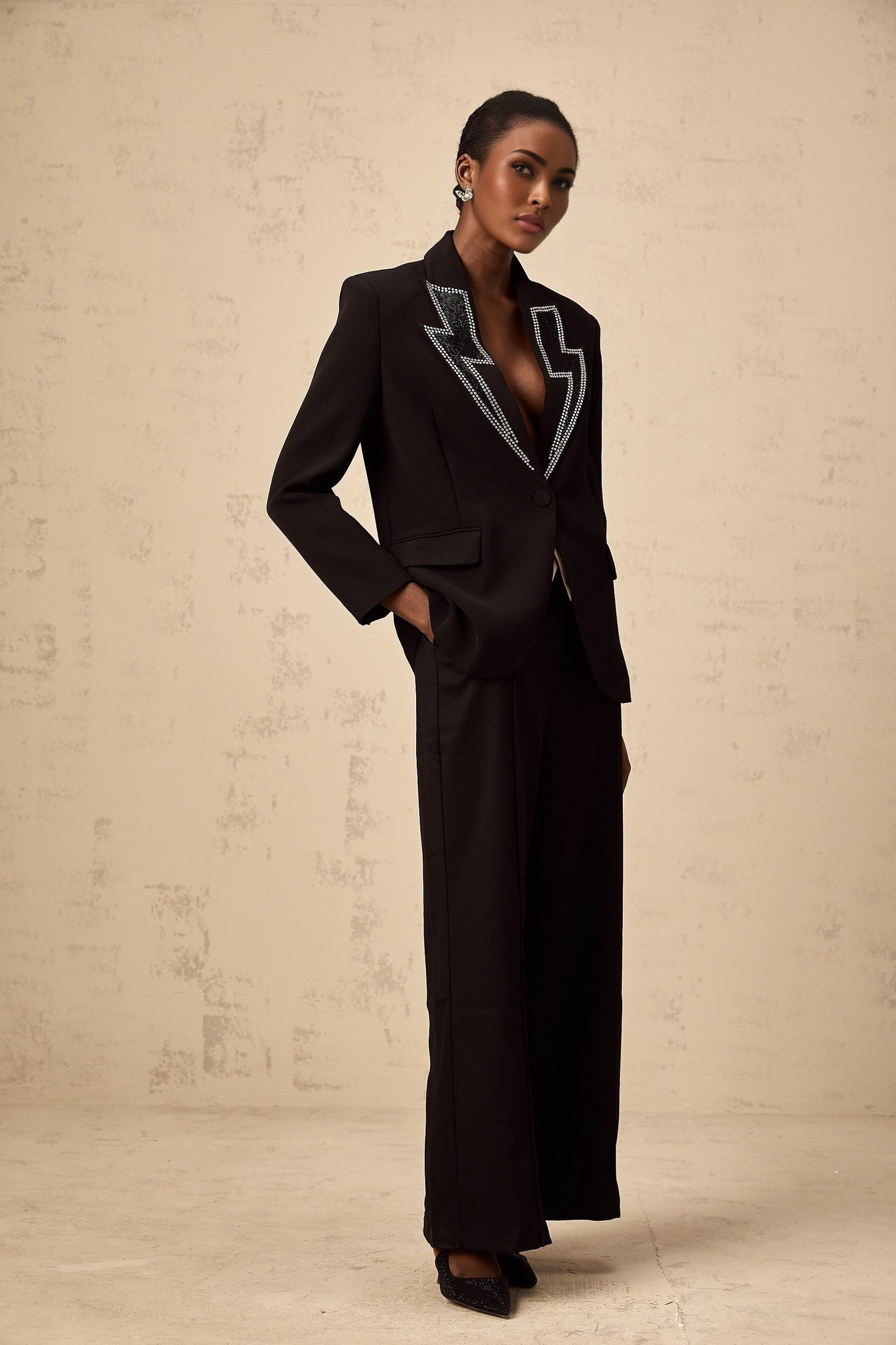 A black blazer with crystal embellishments in the shape of lightning bolts on the lapels and sleeves