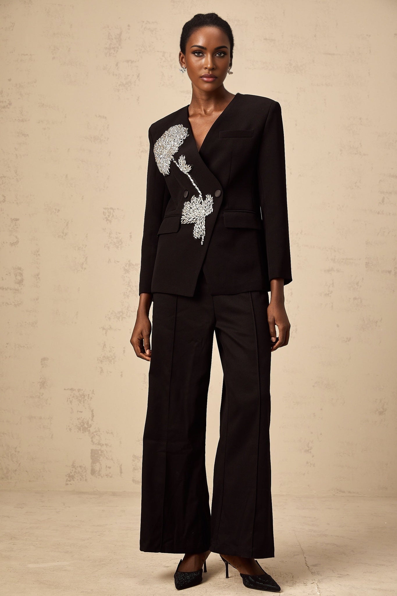 A black blazer with floral embellishments featuring a pattern of delicate flowers across the fabric