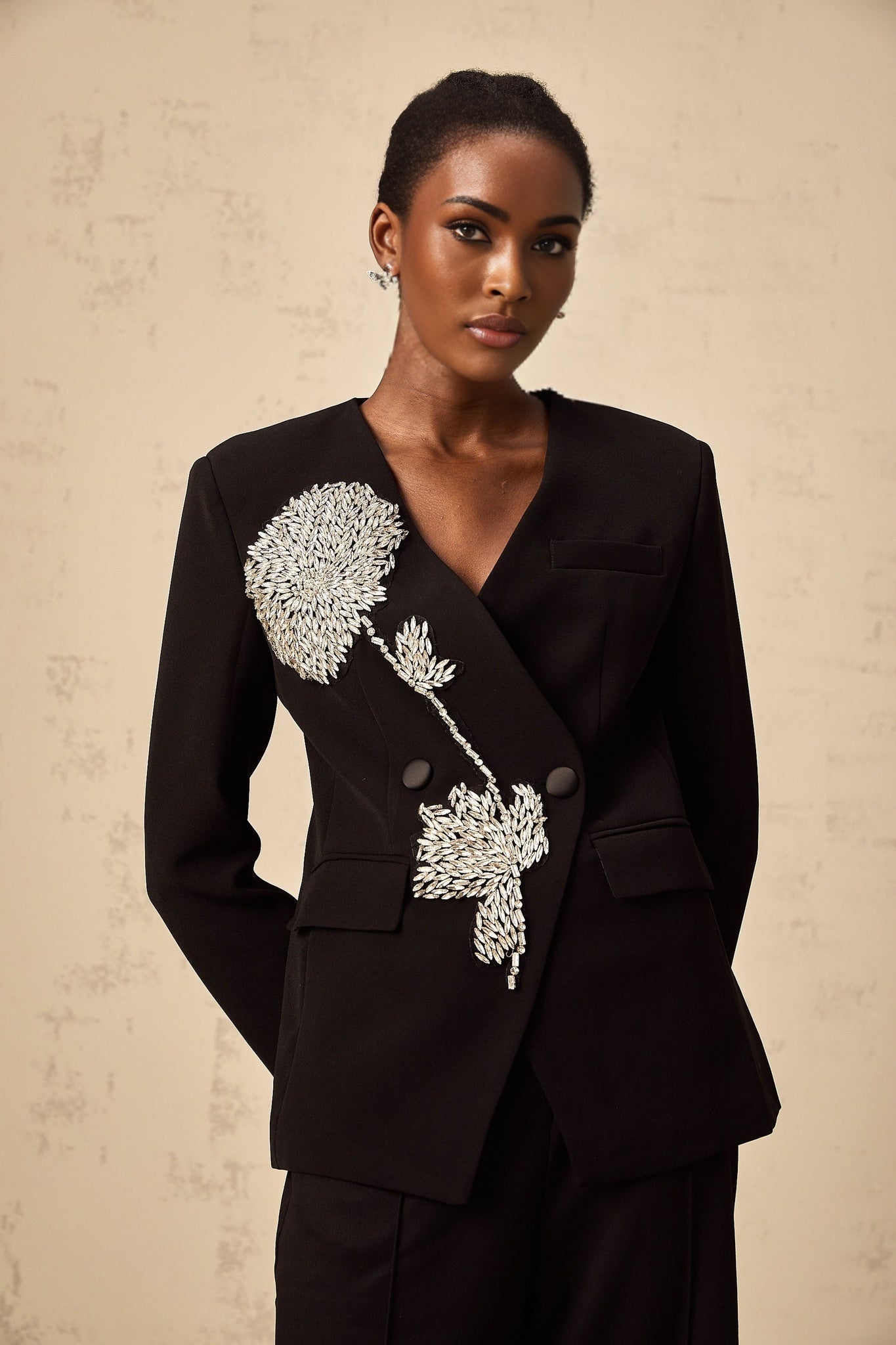 A black blazer with floral embellishments featuring a pattern of flower motifs across the fabric