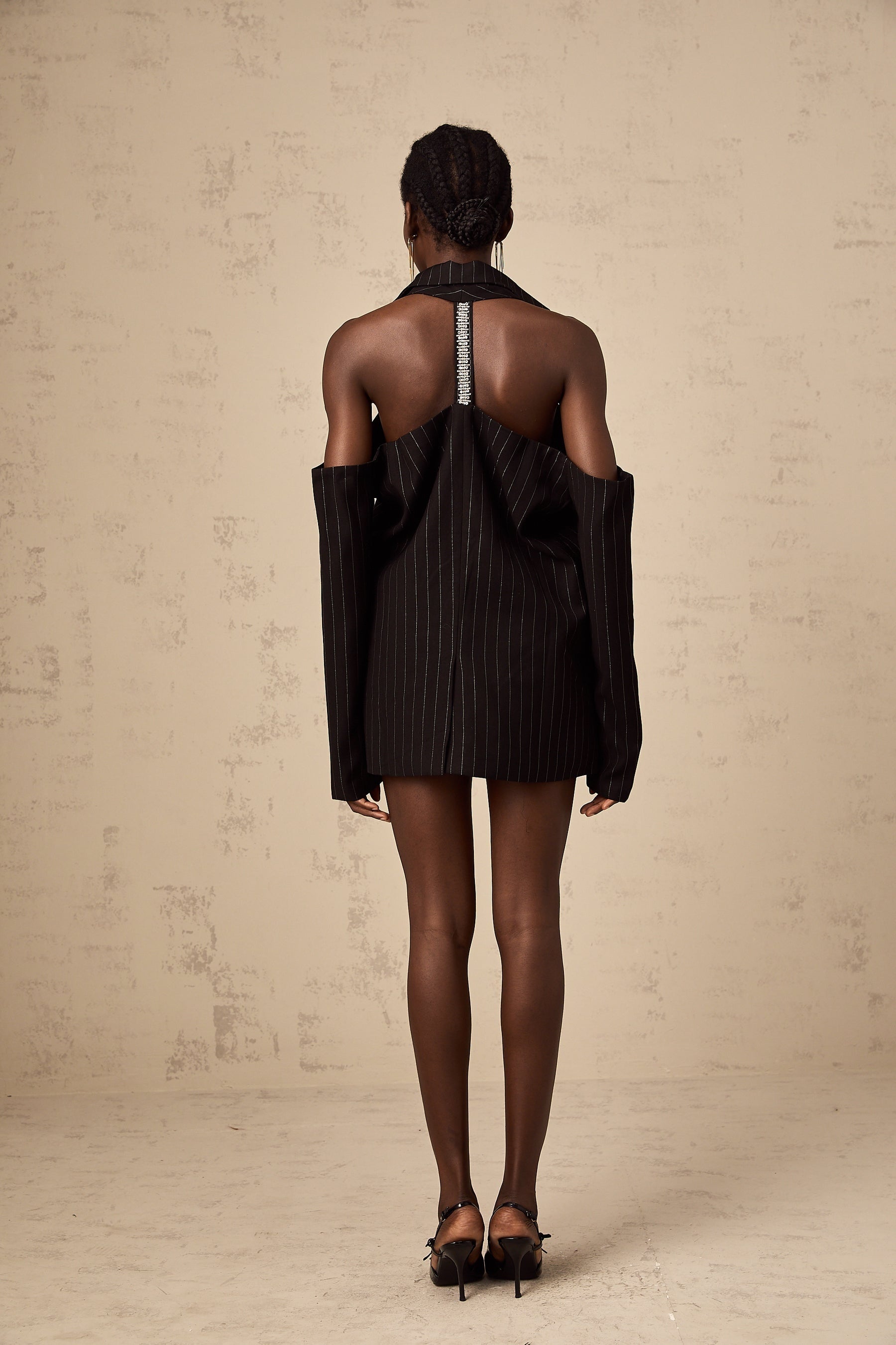 A black blazer with white stripes featuring an open back design displayed on a plain background