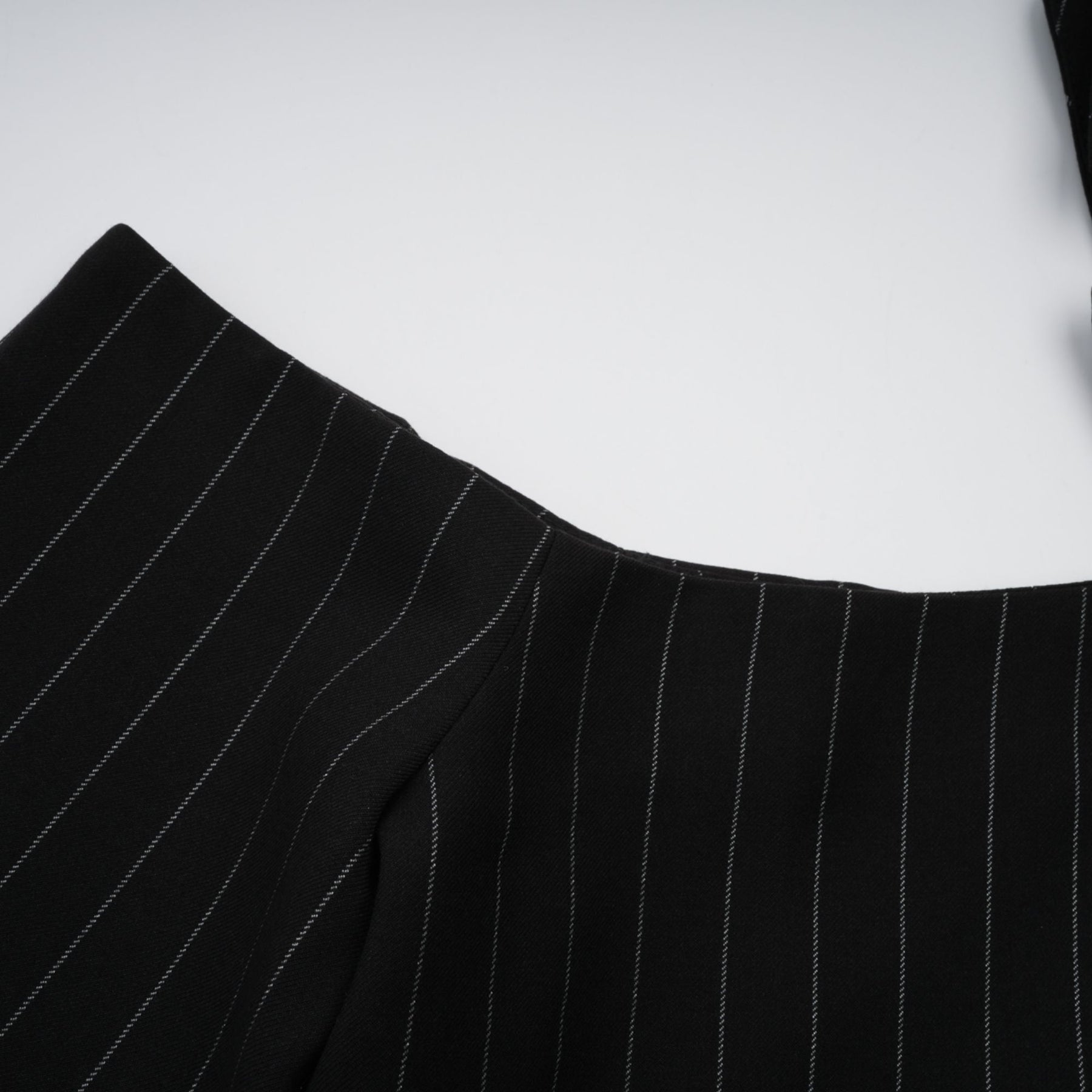 A black blazer with white stripes featuring an open back design Stefania brand
