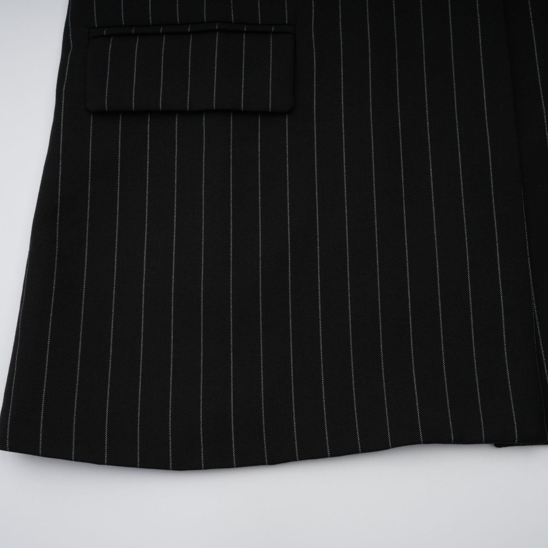 A black blazer with white stripes featuring an open back design worn by a model
