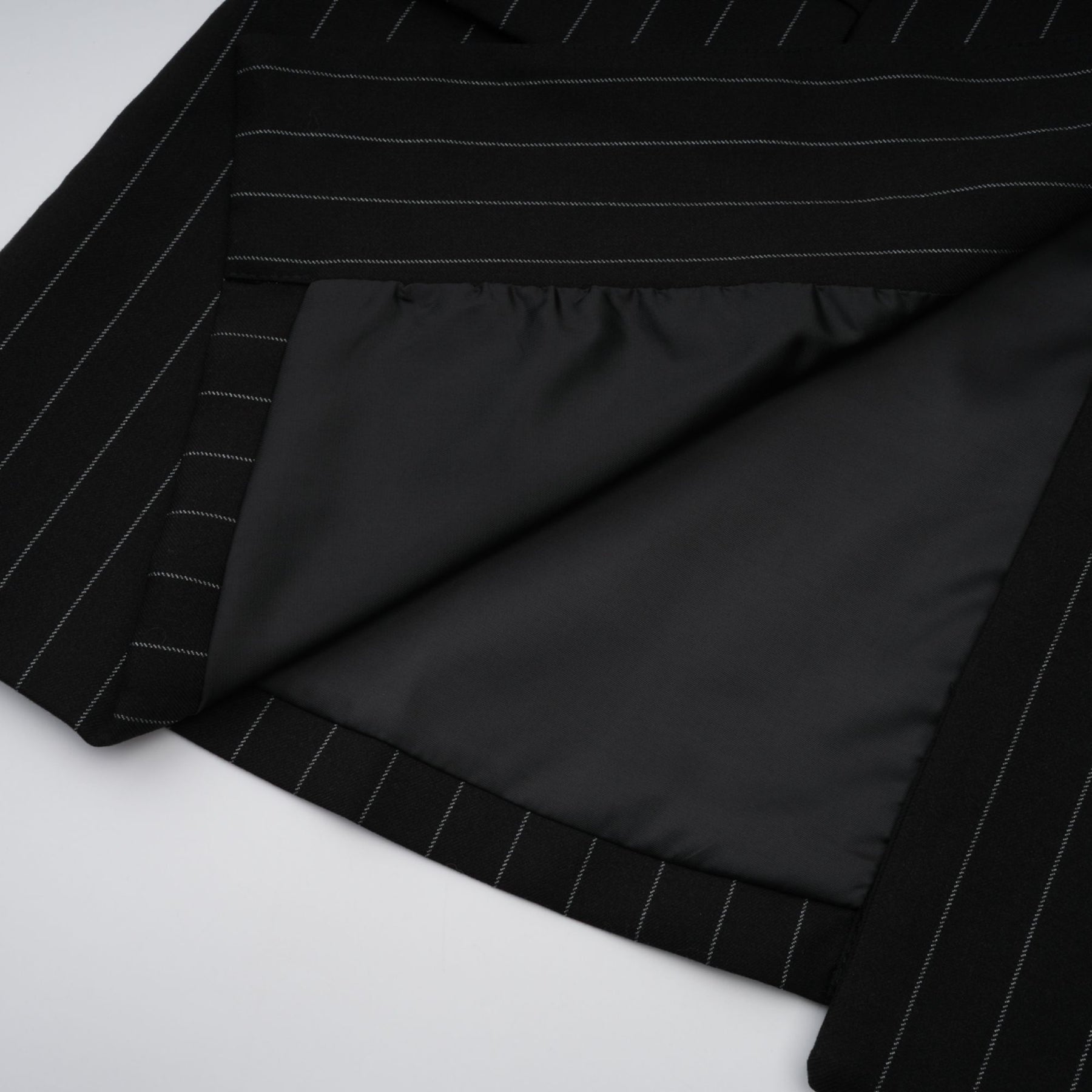 A black blazer with white stripes featuring an open back design worn by a model