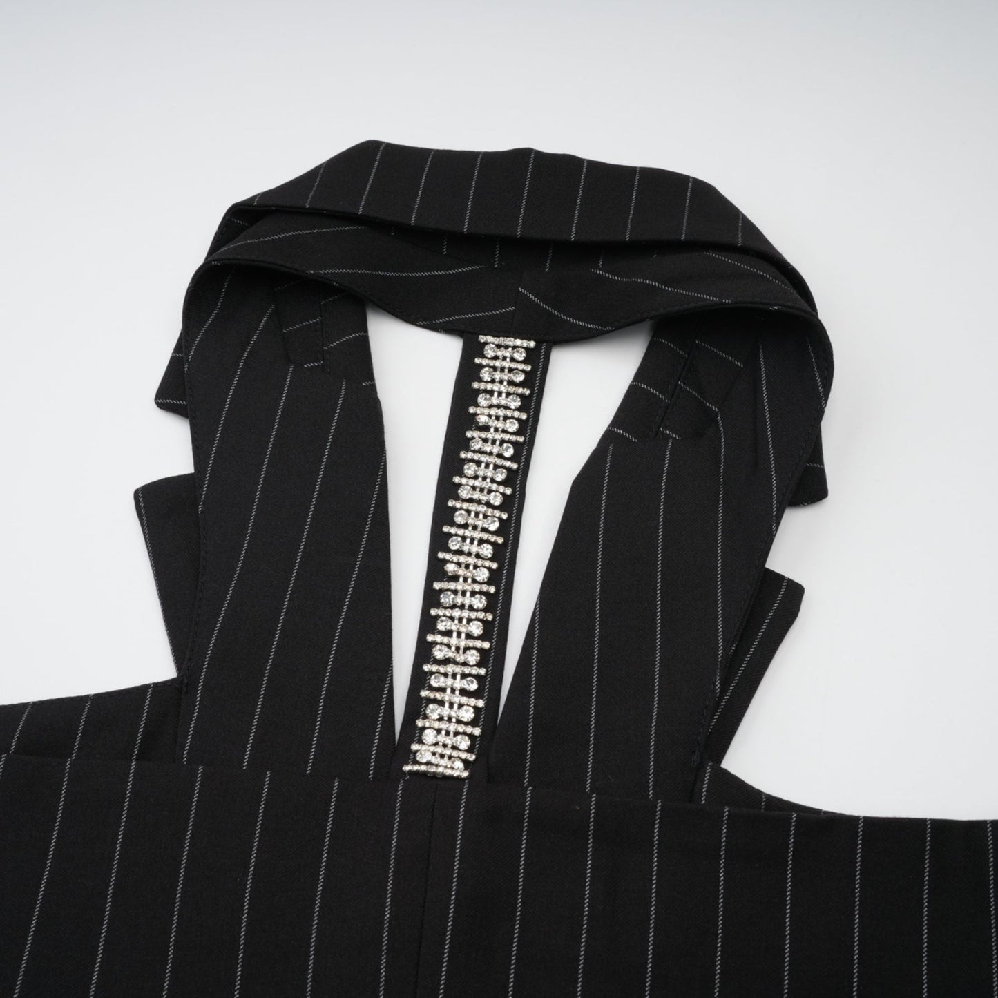 A black blazer with white stripes featuring an open back design worn by a model