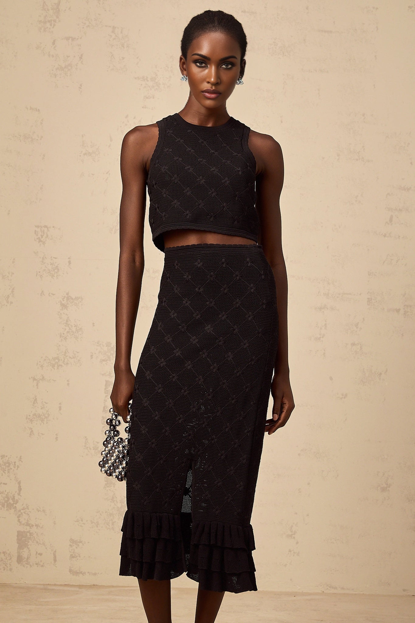 A black crochet knit matching set featuring a top and skirt Joelle design with intricate pattern details and textured fabric