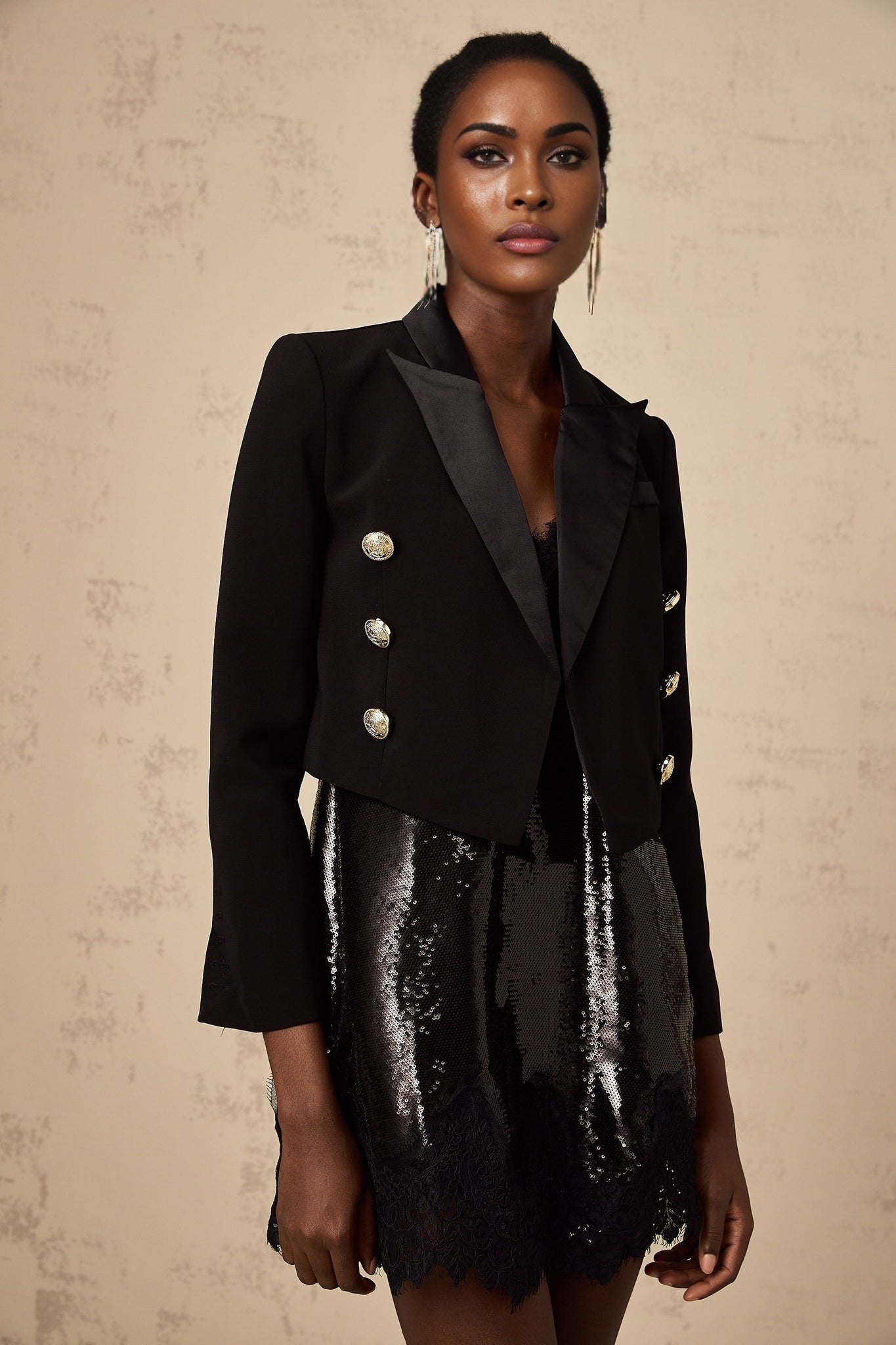 A black cropped blazer with doublebreasted styling named Giulia worn by a model against a plain background