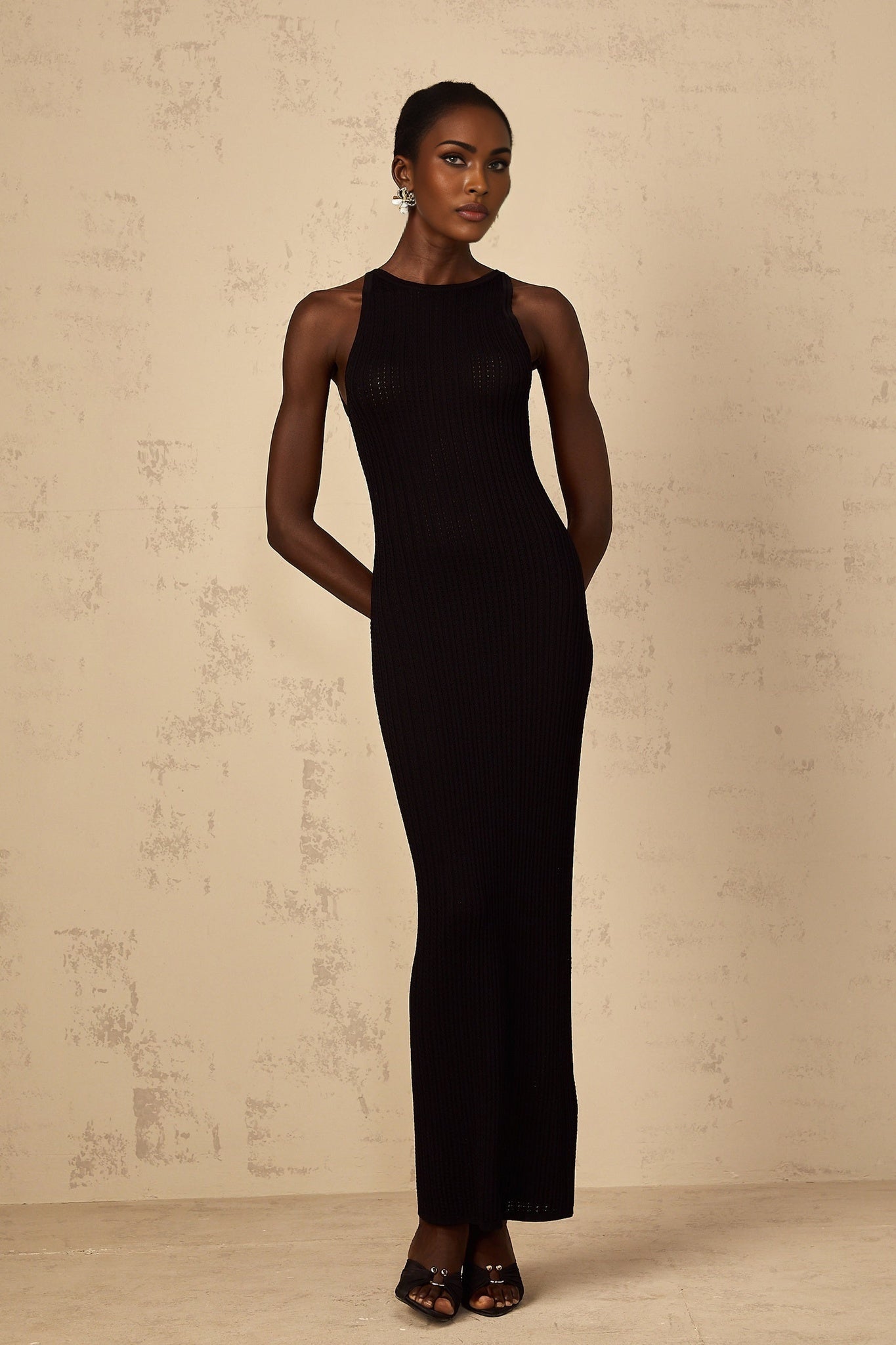 A black fitted maxi dress with ribbed knit fabric and a long form fitting silhouette
