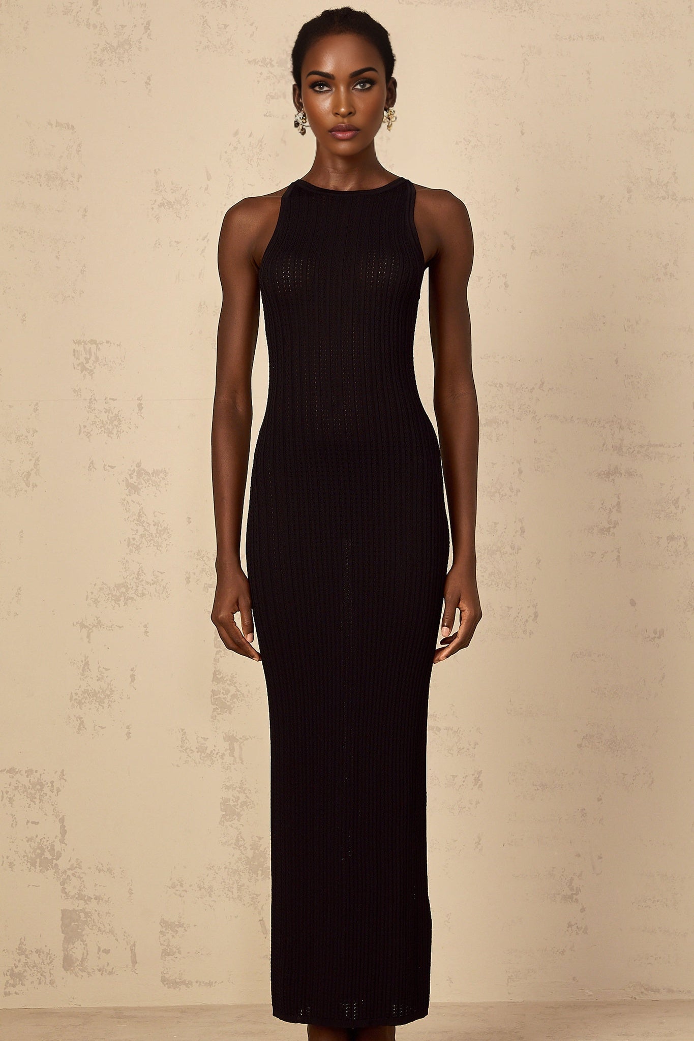 A black fitted ribbed knit maxi dress on a plain background