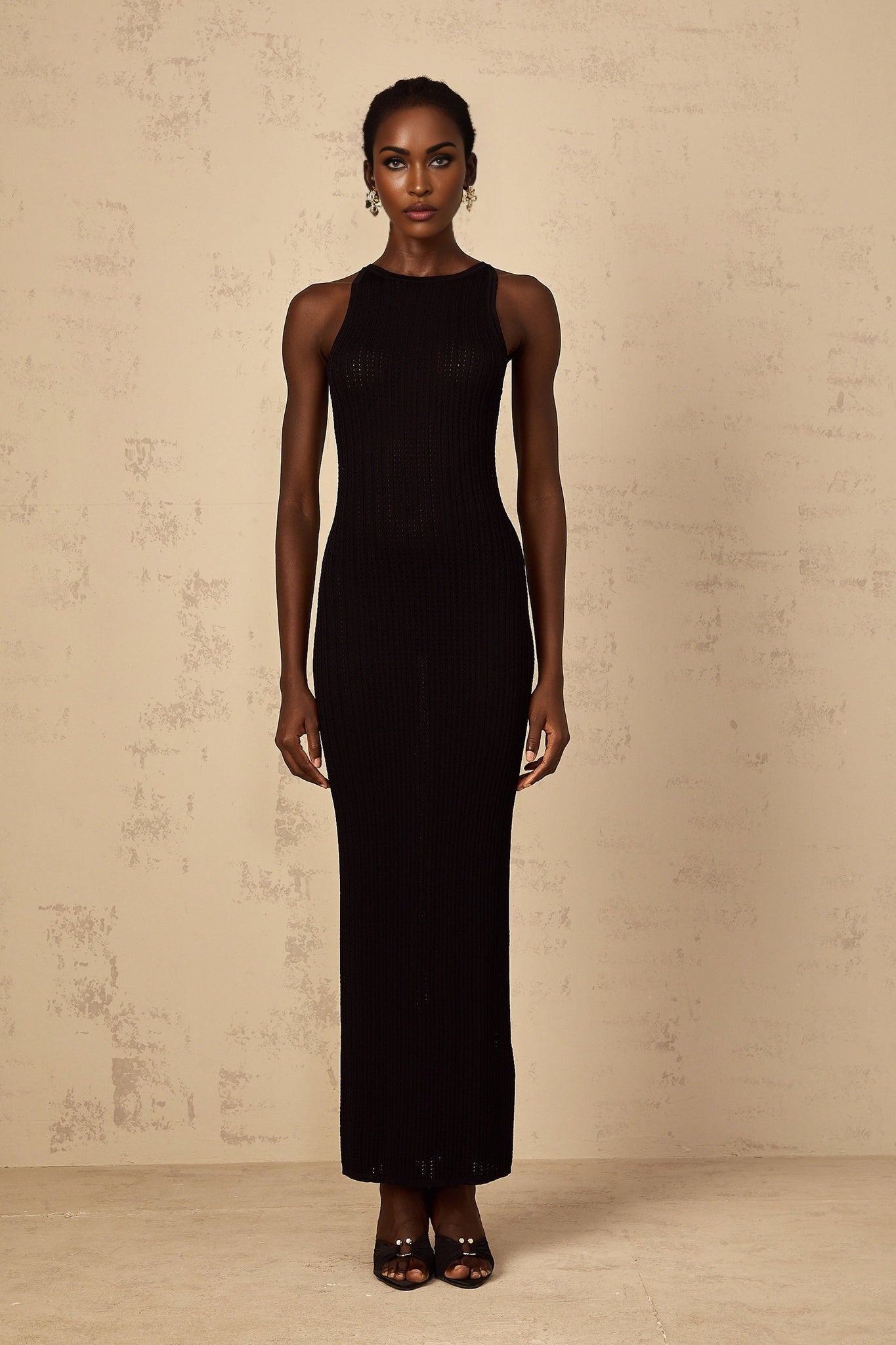 A black fitted ribbed knit maxi dress with long sleeves and a form fitting silhouette