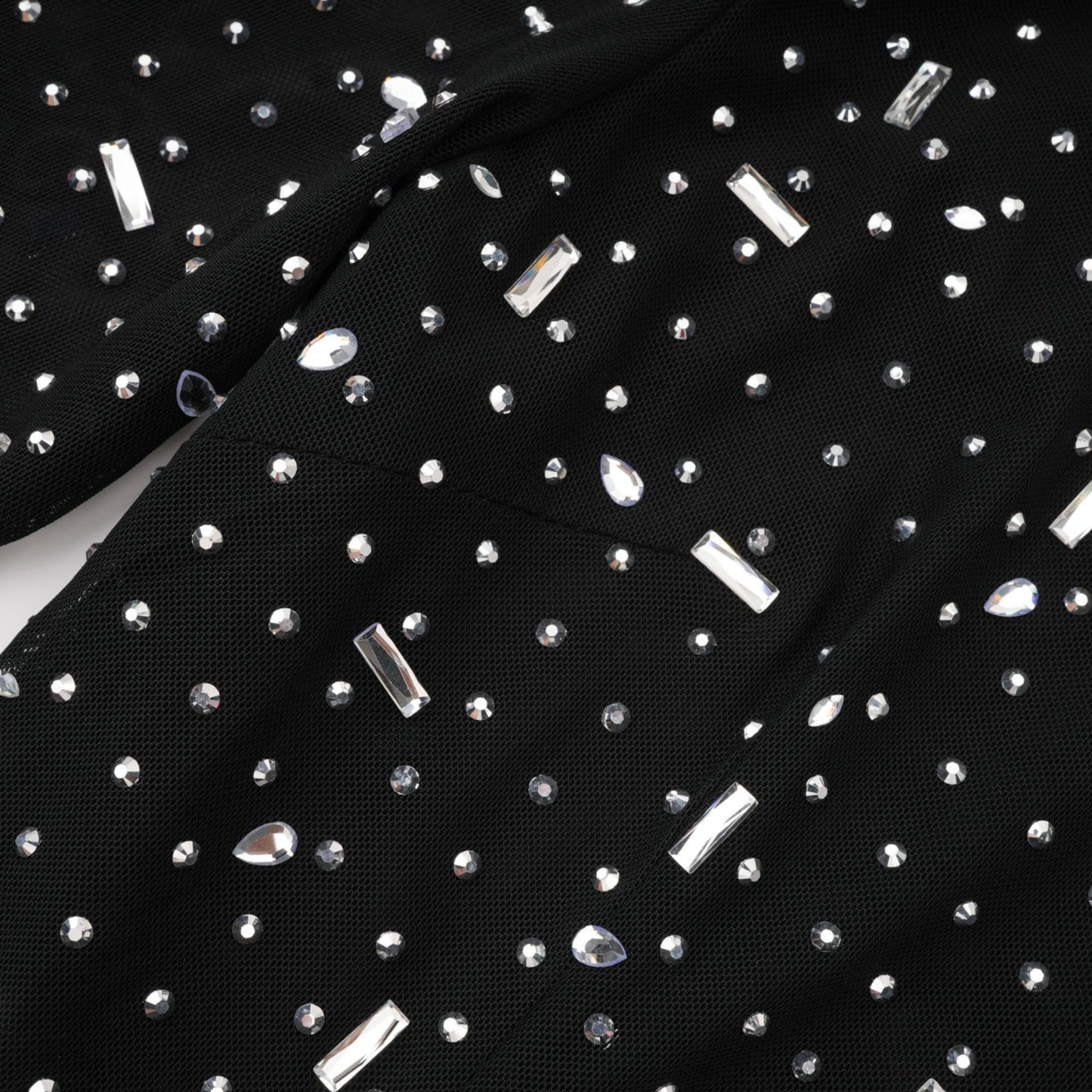 A black floor length maxi dress with sheer panels and embellished details worn by a model against a plain background