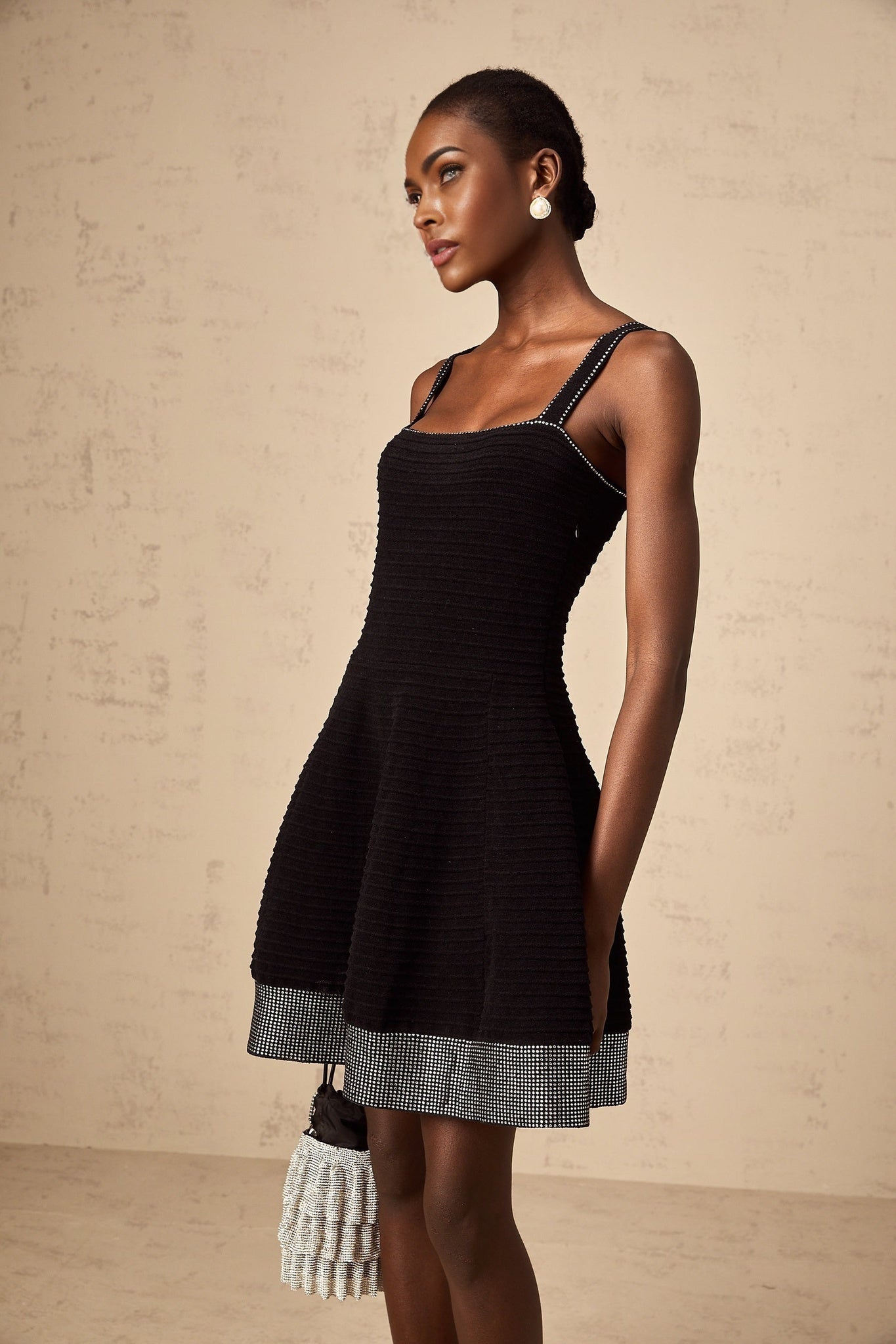 A black knit mini dress with a flared skirt and studded details named Eliane