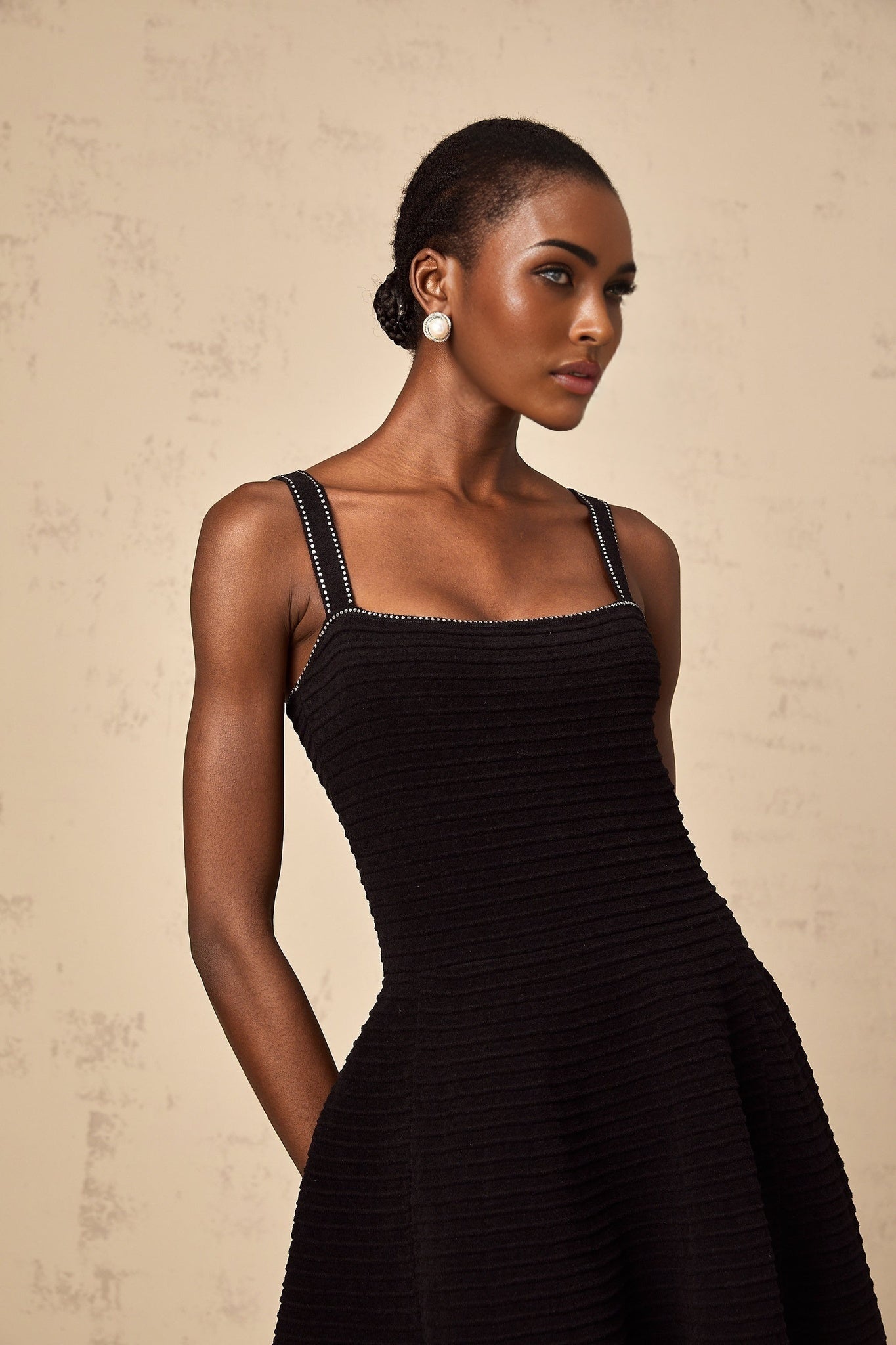 A black knit mini dress with flared skirt and studded embellishments called Eliane