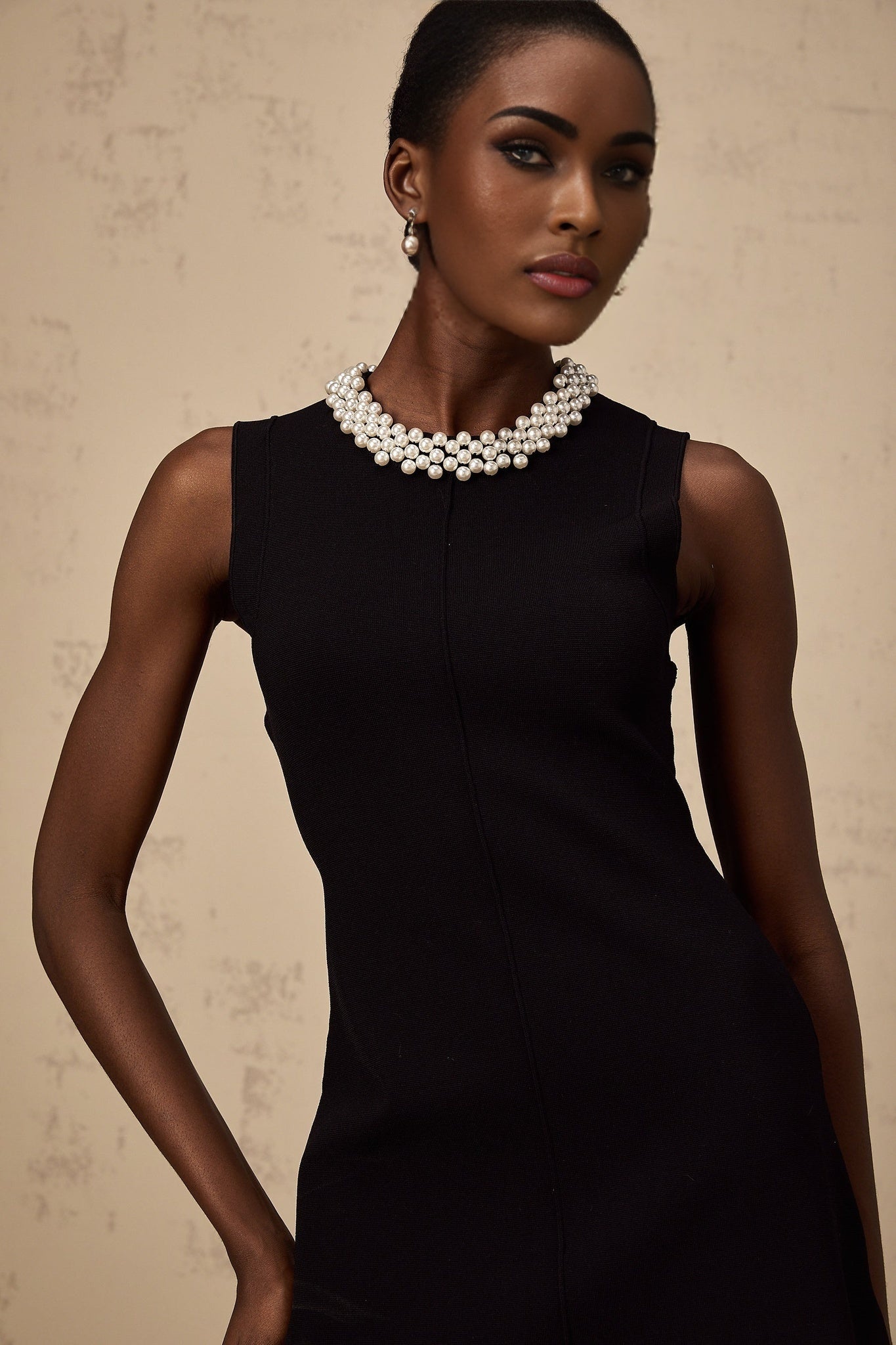 A black knitted mini dress with ruffled details and faux pearl embellishments named Elodie