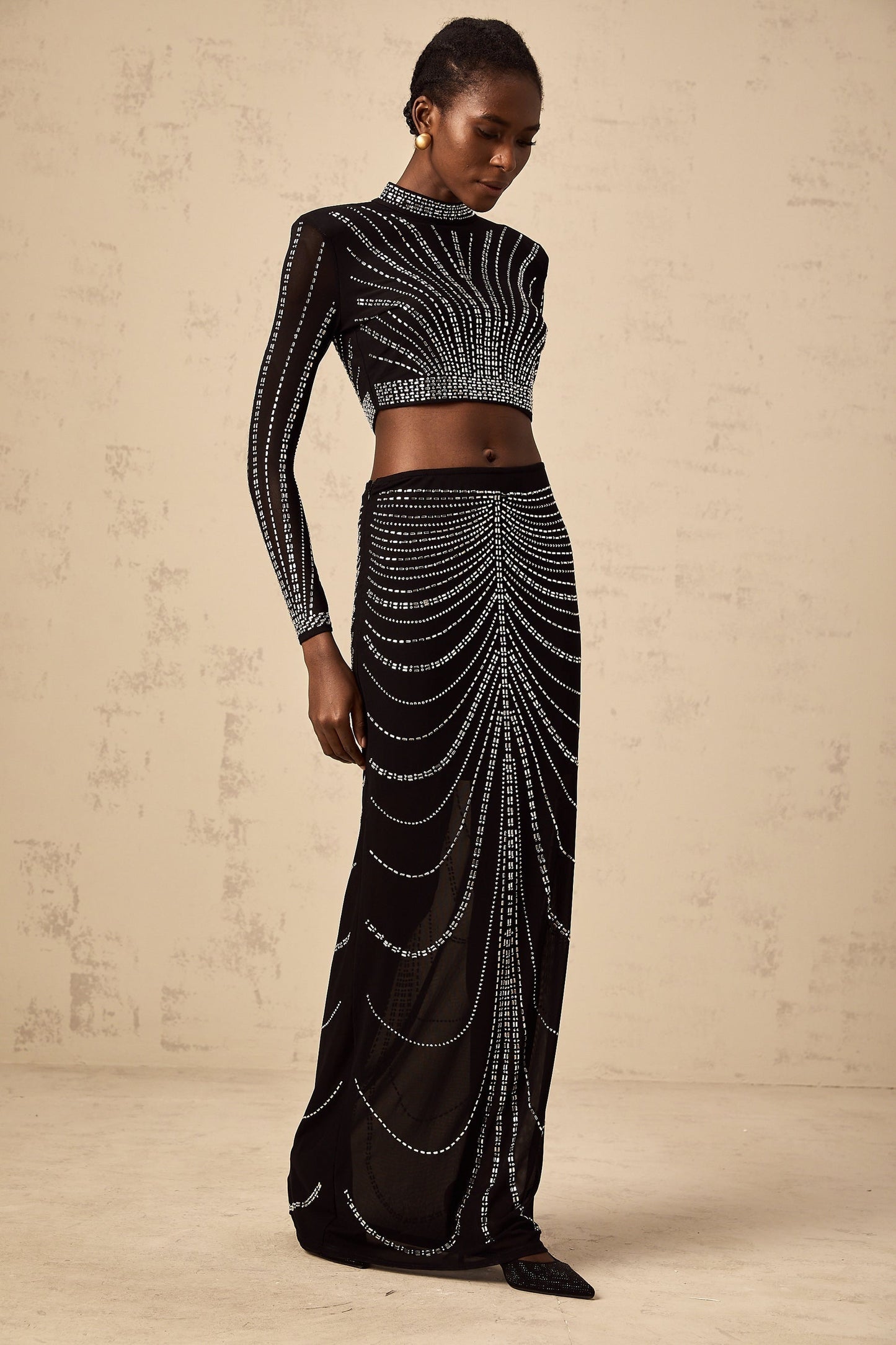 A black matching set consisting of a mesh top and skirt adorned with rhinestones featuring a shimmering and elegant design