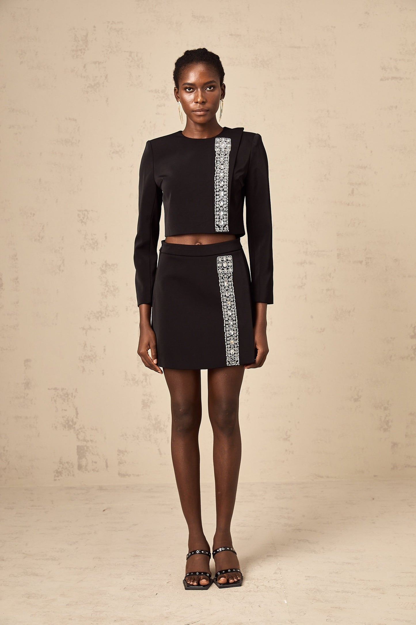 A black matching set consisting of a top and skirt adorned with crystal embellishments named Nadia