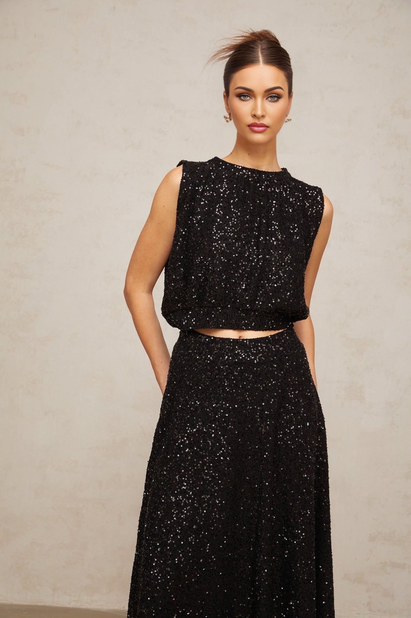 A black matching set featuring a sequined knit vest and skirt with sparkly details and a coordinated design
