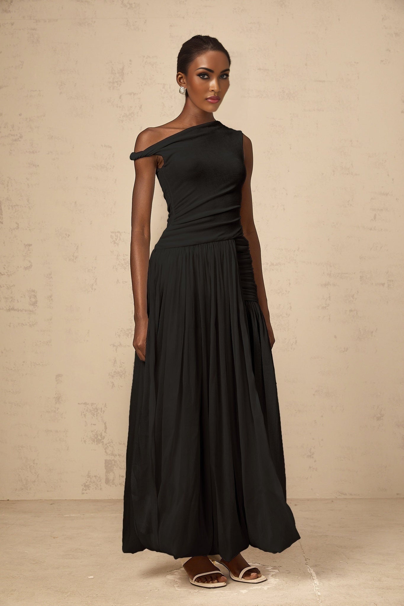 A black maxi dress with a single shoulder strap and shirred panels featuring a fitted bodice and flowing skirt
