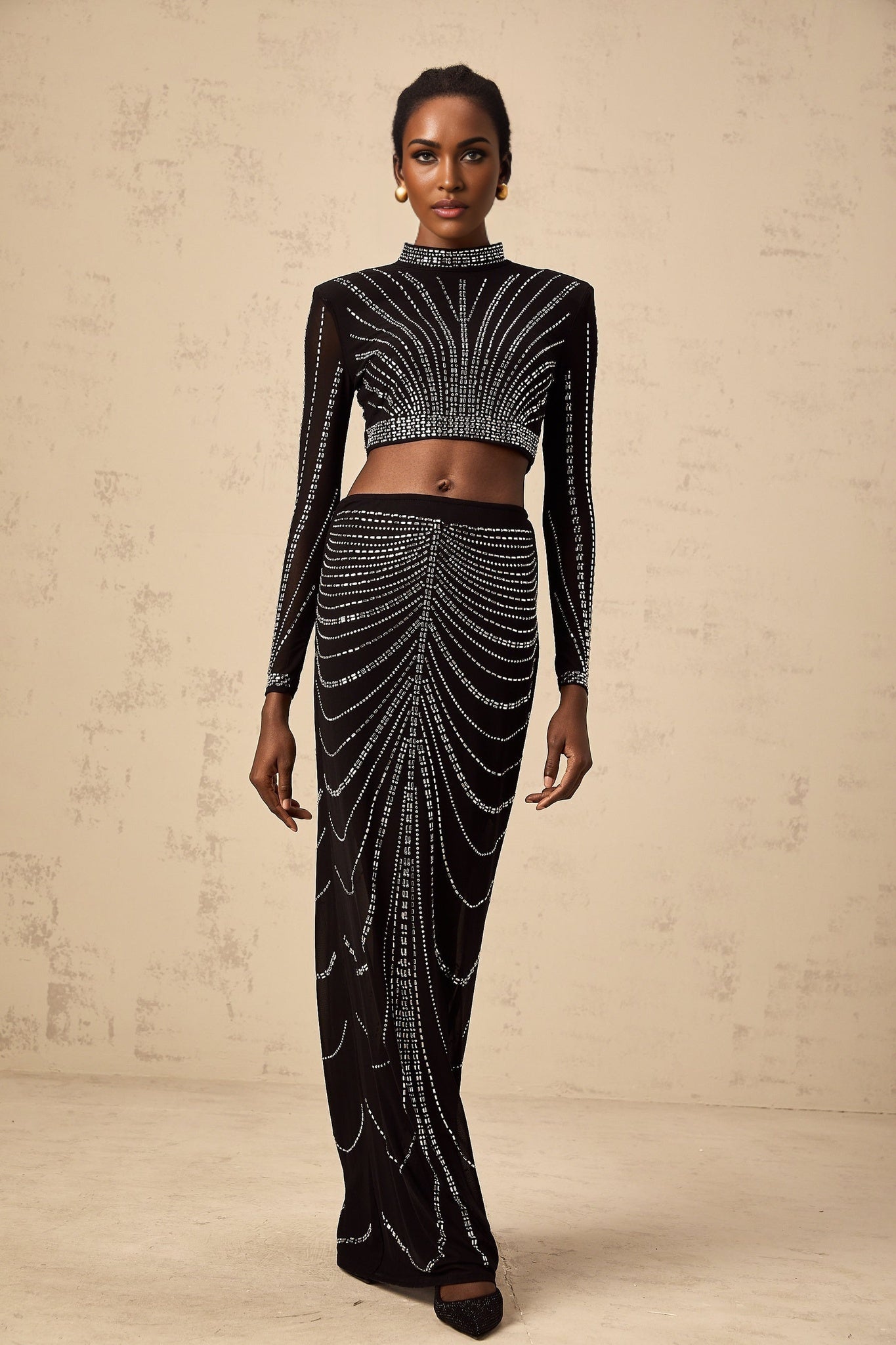 A black mesh twopiece outfit featuring a top and skirt adorned with rhinestone embellishments creating a sparkling effect on a sheer background