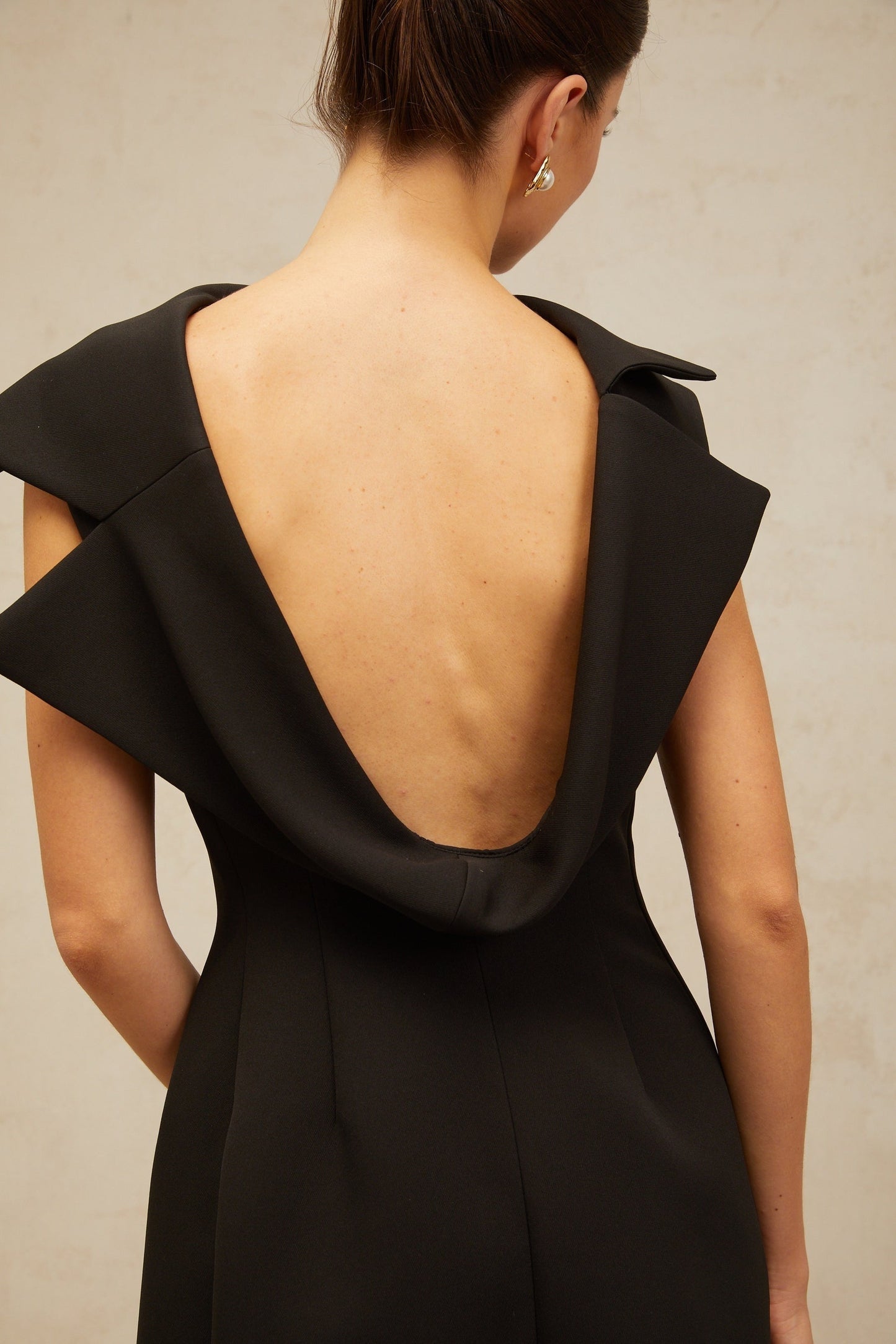A black midi dress with an open back and deconstructed design elements named Leonore