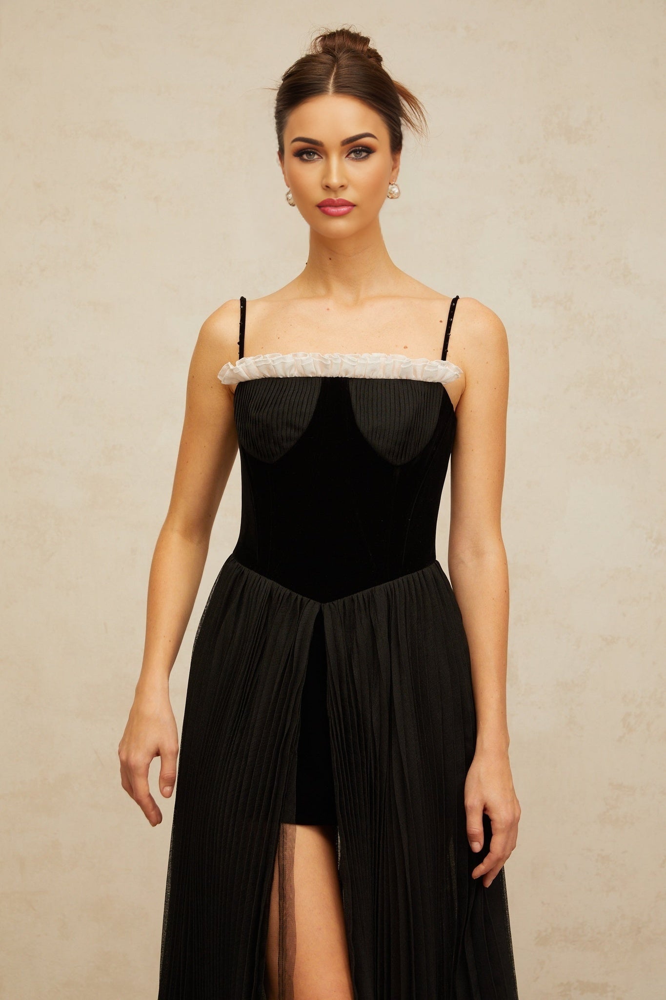 A black midi dress with velvet panels and pleated details featuring a flowy silhouette and elegant design