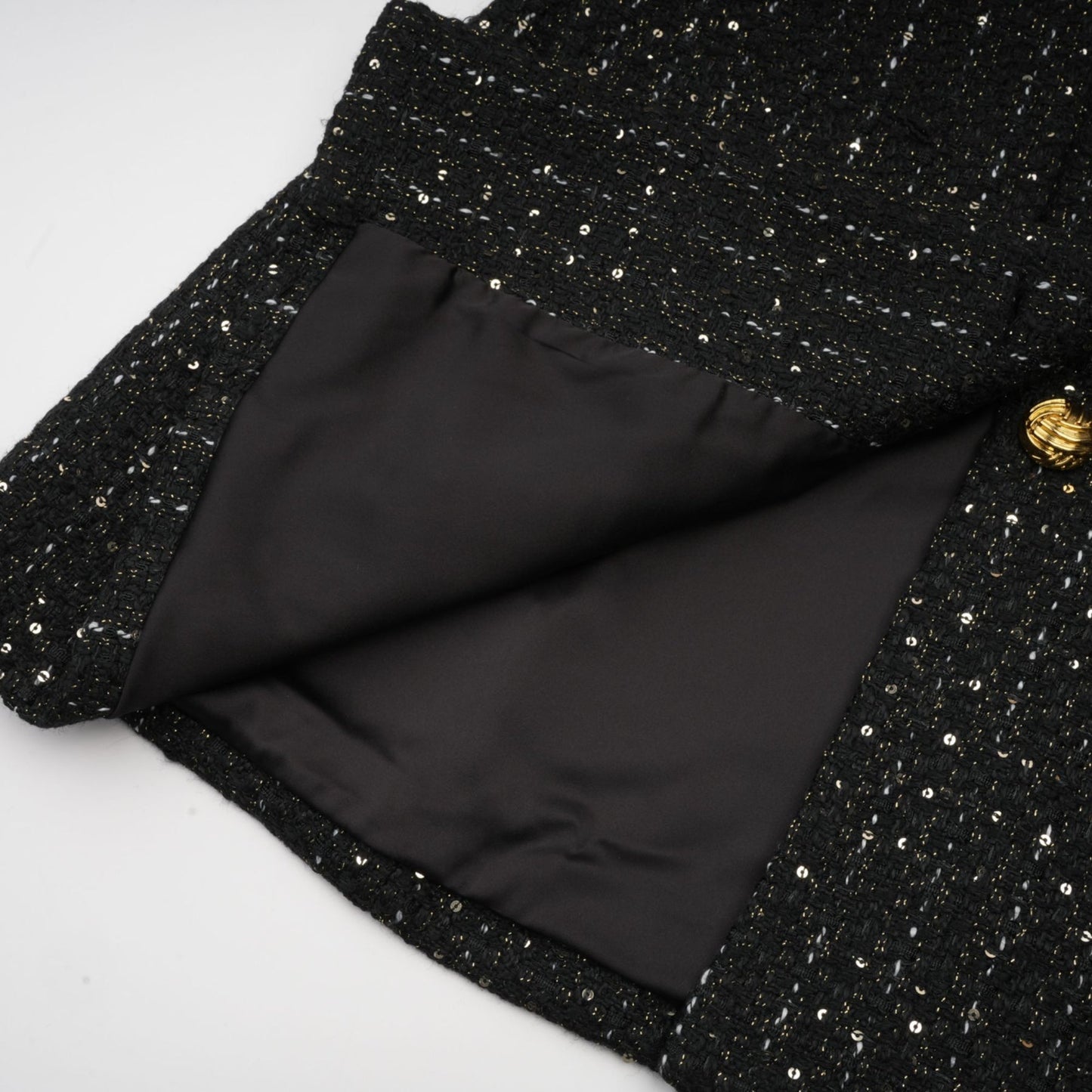 A black mini dress featuring a tweed fabric with sequin panels named Audrey combining classic and glamorous elements in a short silhouette