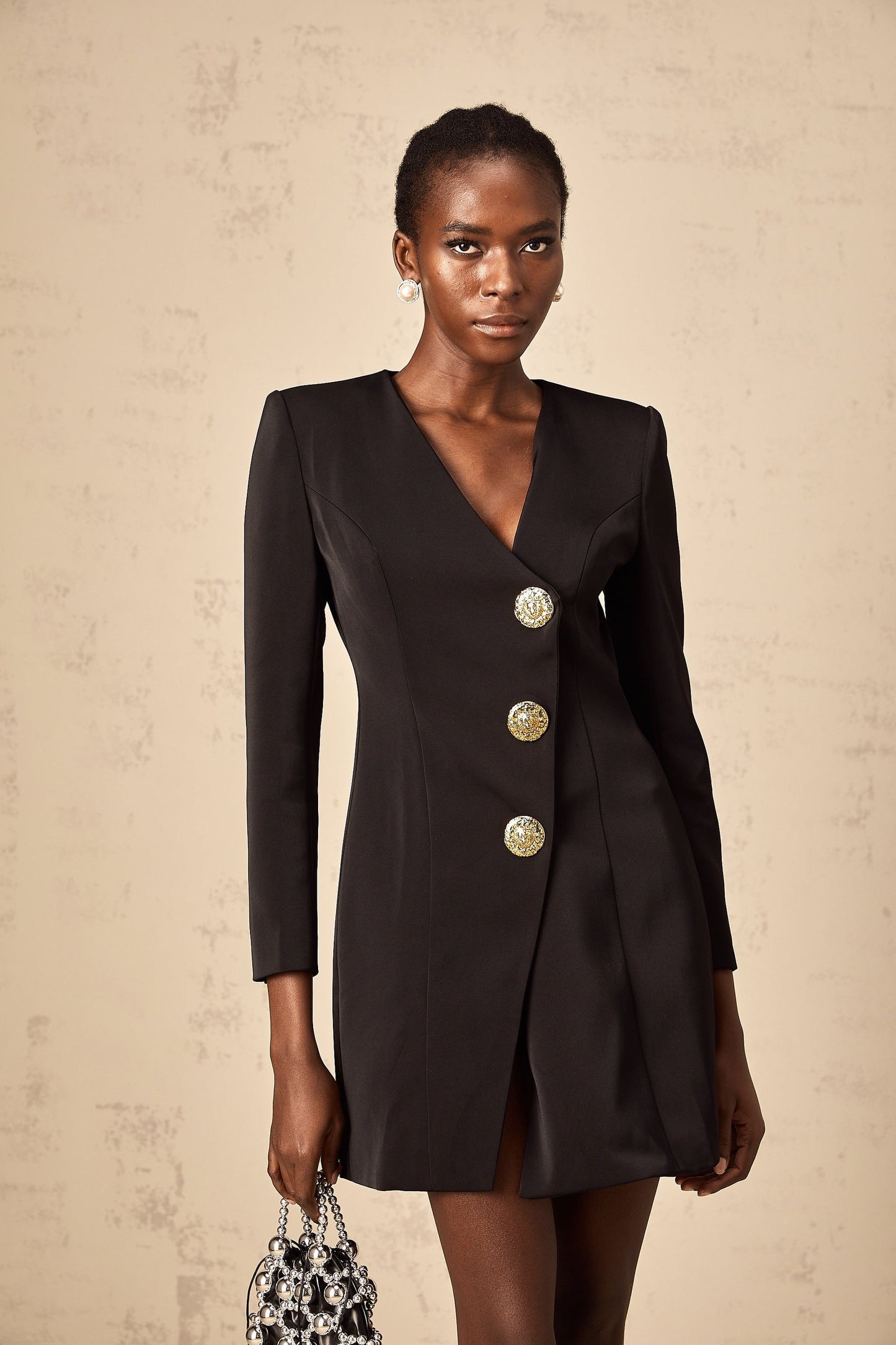A black mini dress with a blazerstyle top featuring decorative lion head details on the front