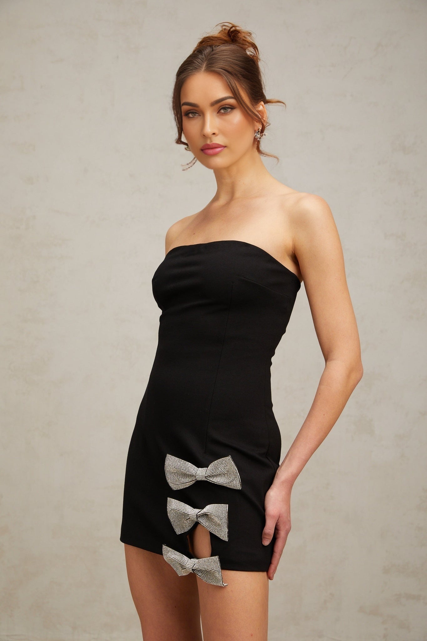 A black mini dress with a fitted silhouette featuring a bowknot detail and studded embellishments