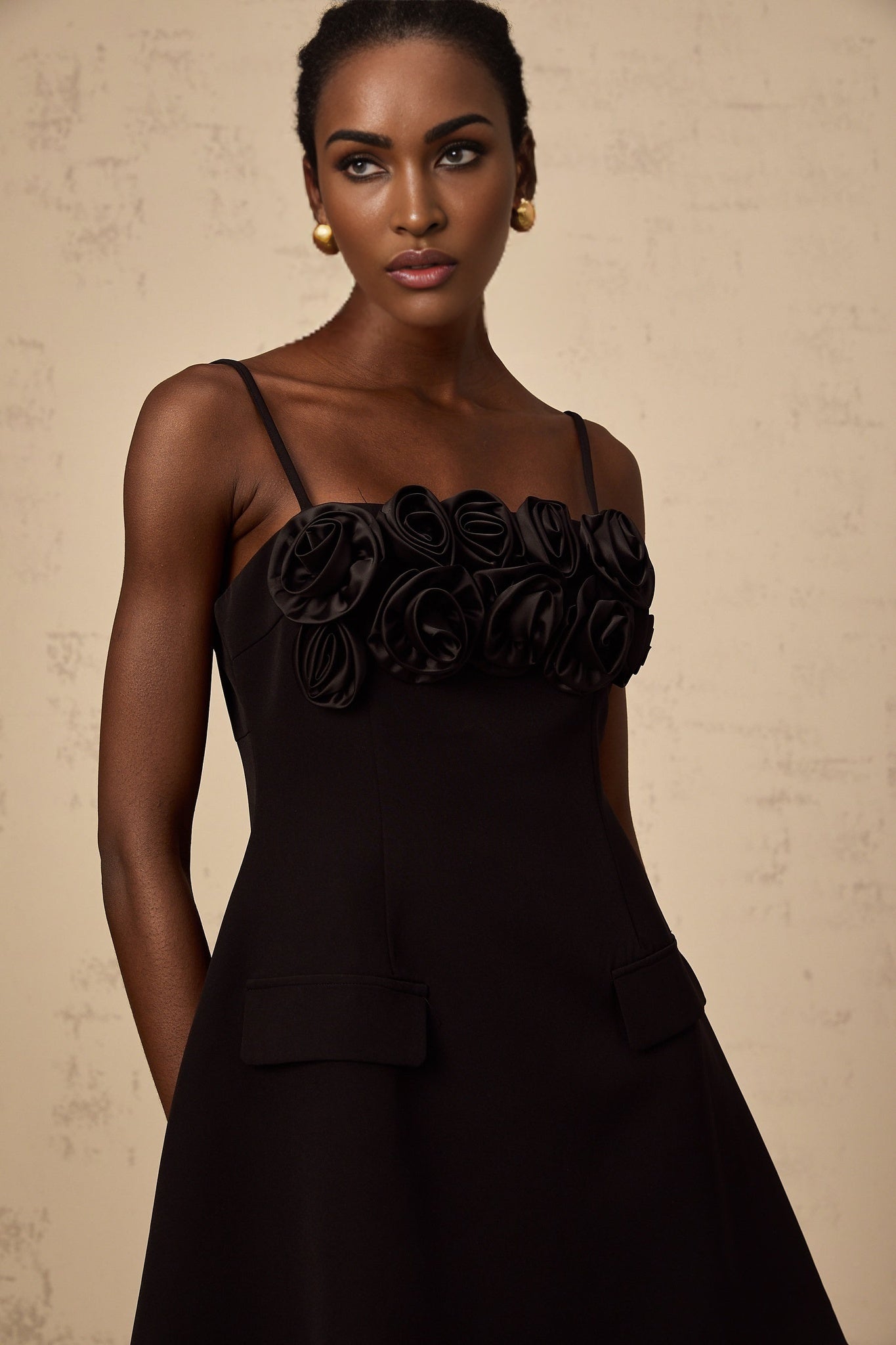 A black mini dress with a flared skirt featuring delicate rose appliques The dress has a fitted bodice and short hemline creating a feminine silhouette
