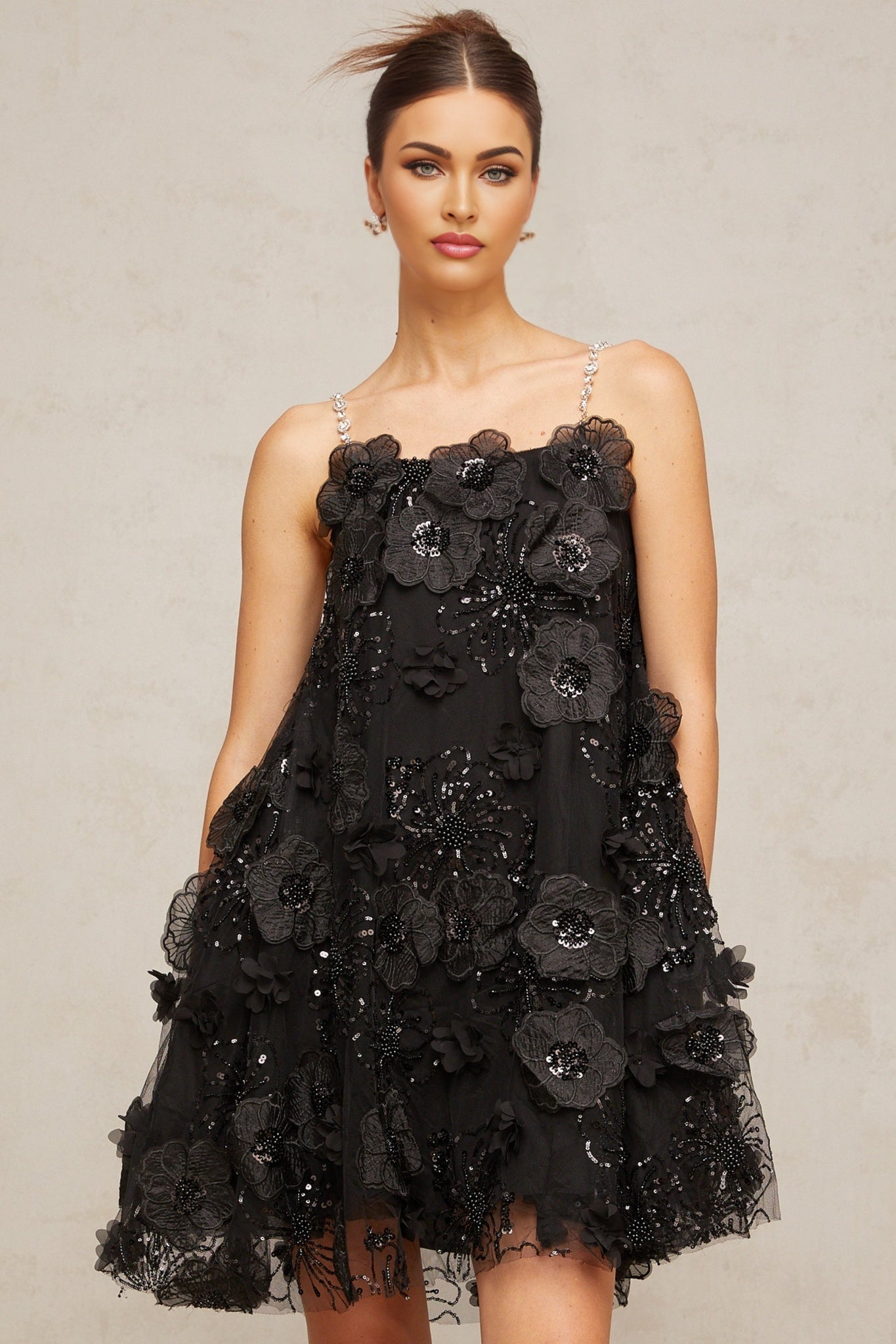 A black mini dress with a floral pattern and crystal embellishments featuring a short hemline and feminine silhouette