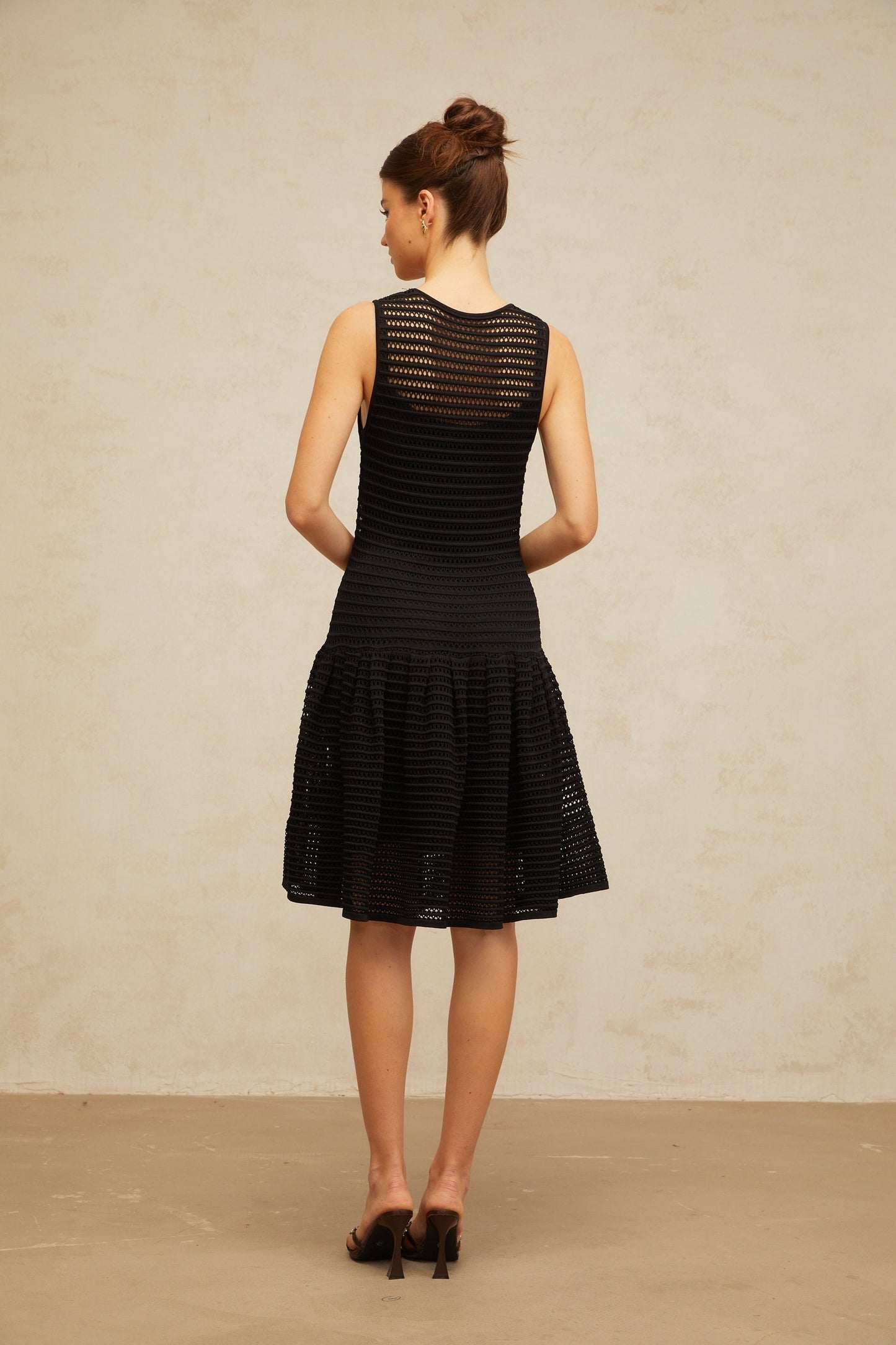 A black mini dress with a flounced hem and pointelle knit pattern featuring a fitted silhouette and short sleeves