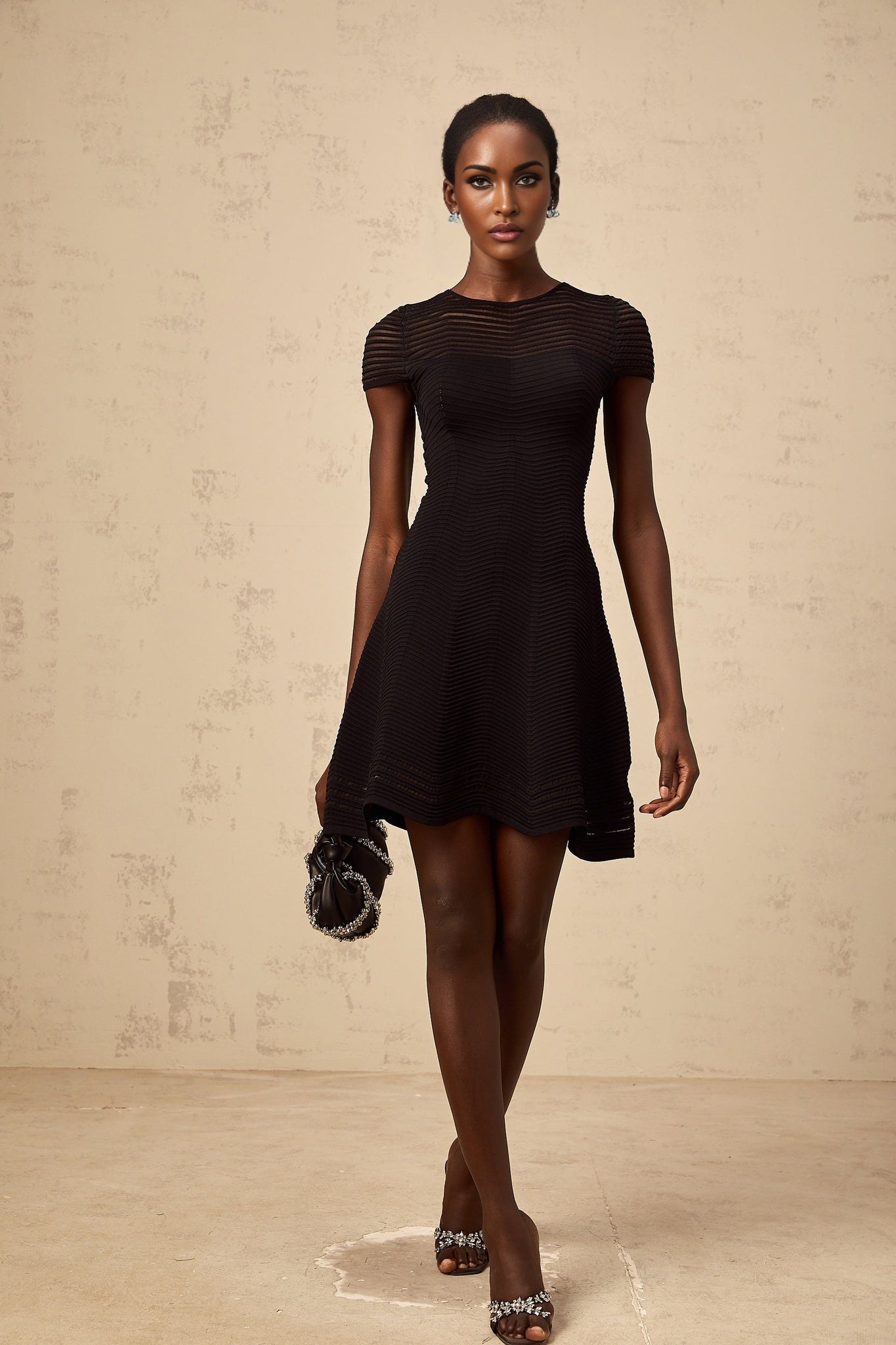 A black mini dress with a wavy crochet texture featuring a short hemline and intricate textured pattern throughout the garment