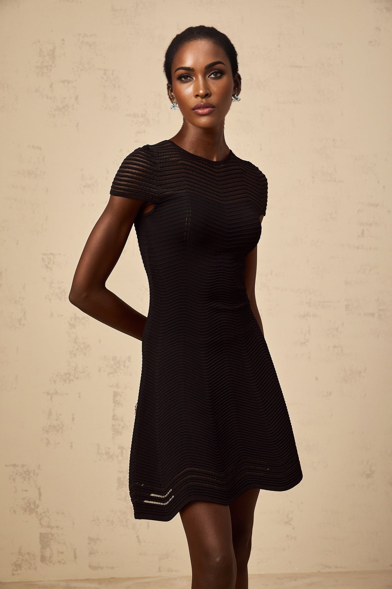 A black mini dress with a wavy crochet texture featuring a textured pattern throughout the garment