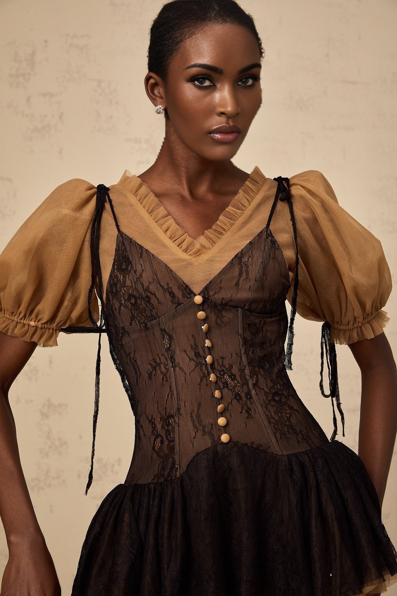 A black mini dress with lace panels featuring a fitted silhouette and delicate lace detailing throughout the bodice and sleeves