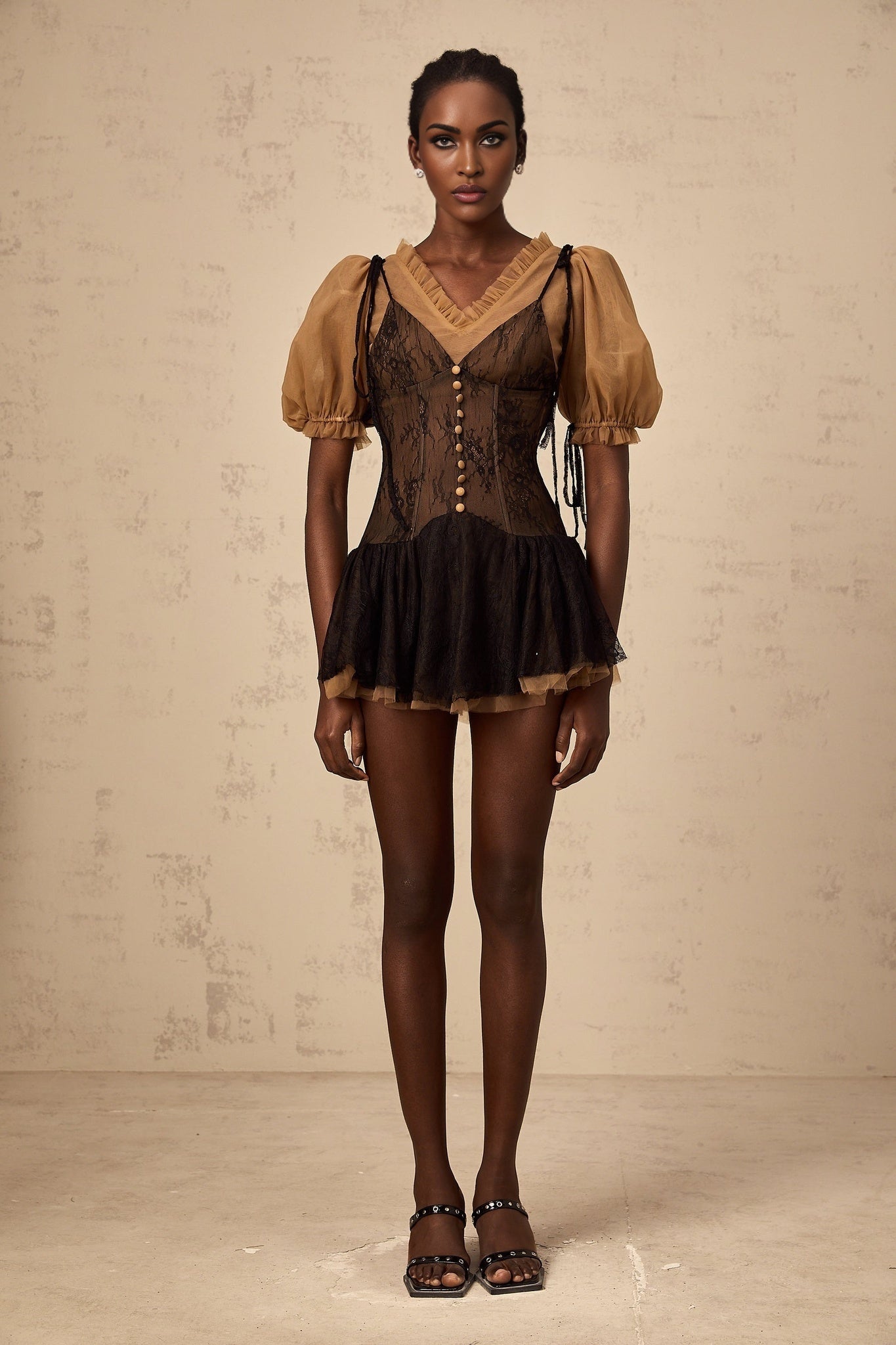 A black mini dress with lace panels featuring a fitted silhouette and delicate lace detailing throughout the bodice and sleeves