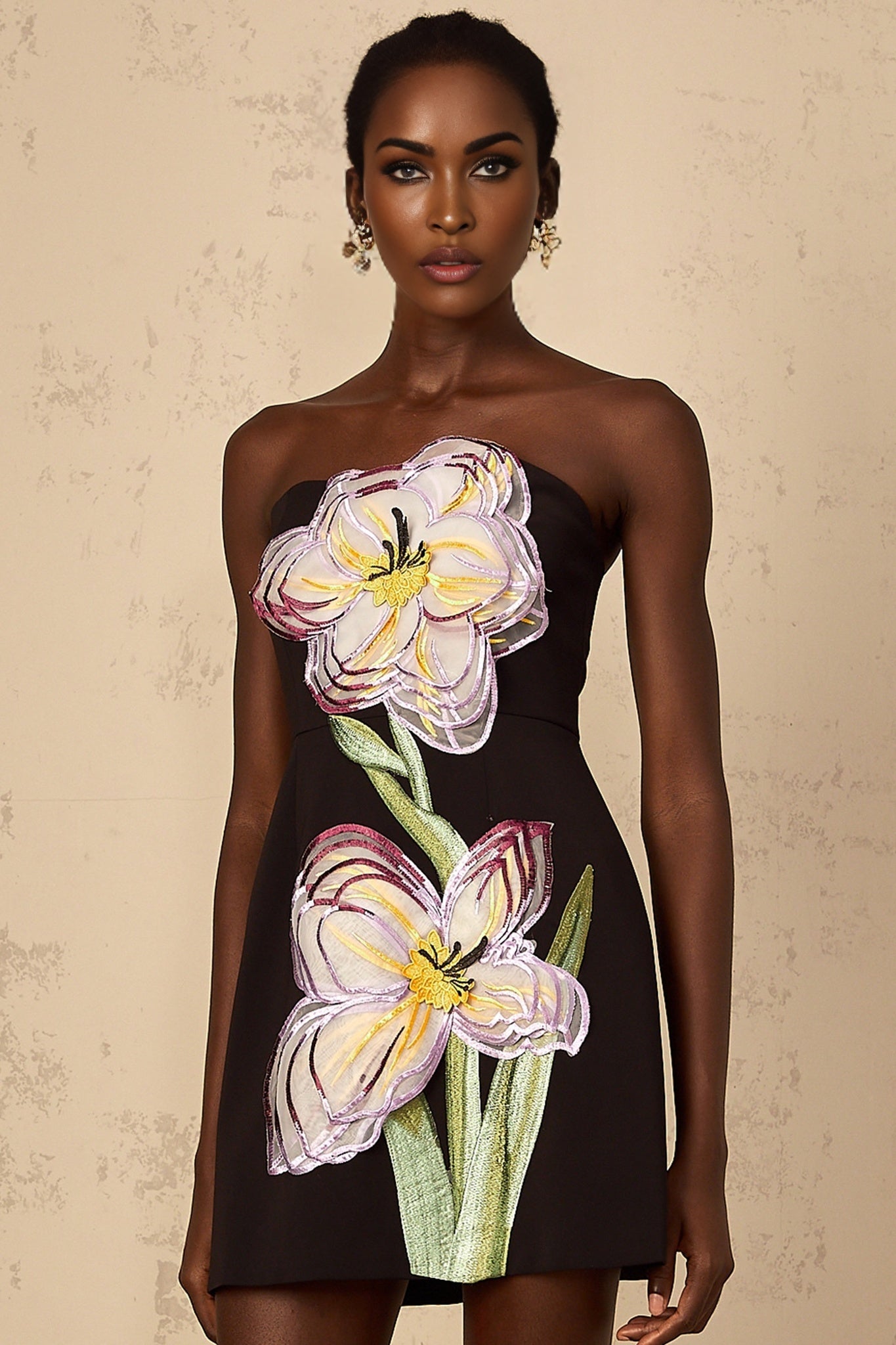 A black mini dress with offshoulder design featuring sequin and floral embroidery details worn by a woman