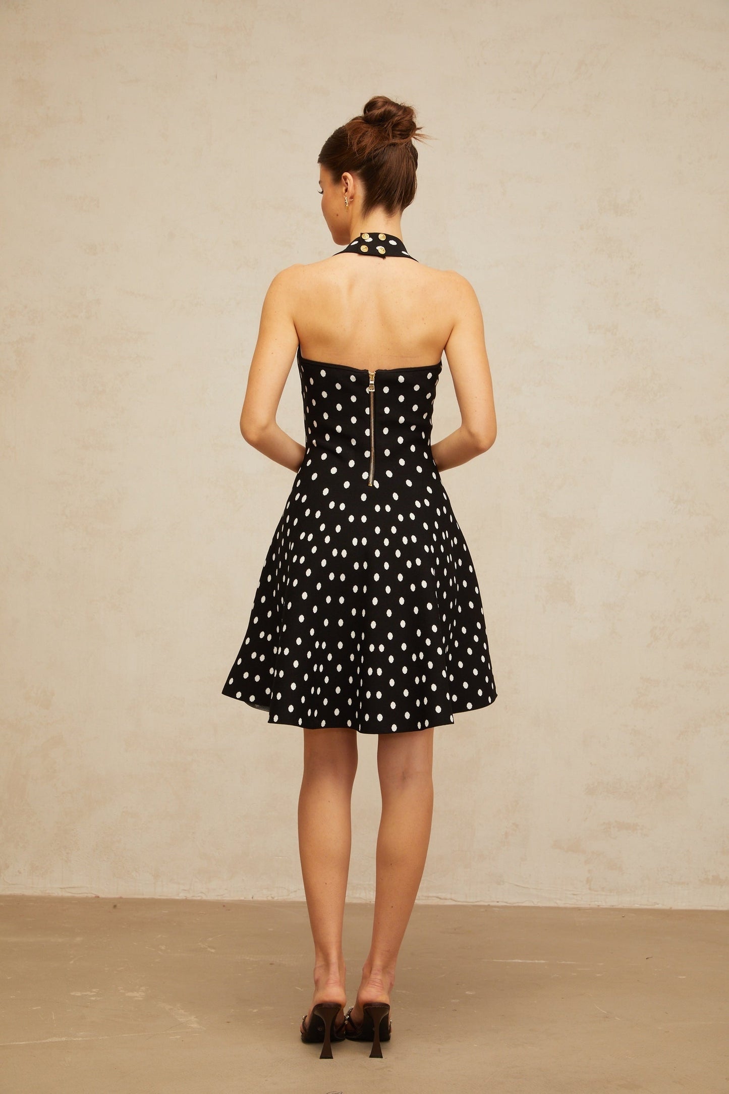A black mini dress with white polka dots made of knit fabric featuring a fitted silhouette and short length